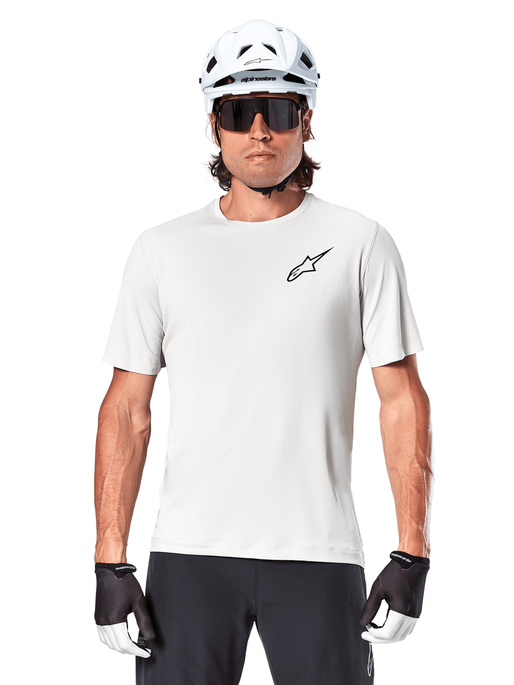 Ciclista con jersey de manga corta Alpinestars A-Aria Astar, color White Dove con pequeño logotipo Astar negro en el pecho, casco de ciclismo blanco, gafas de sol negras y guantes blancos y negros, equipamiento de alto rendimiento para MTB y conducción fuera de carretera
