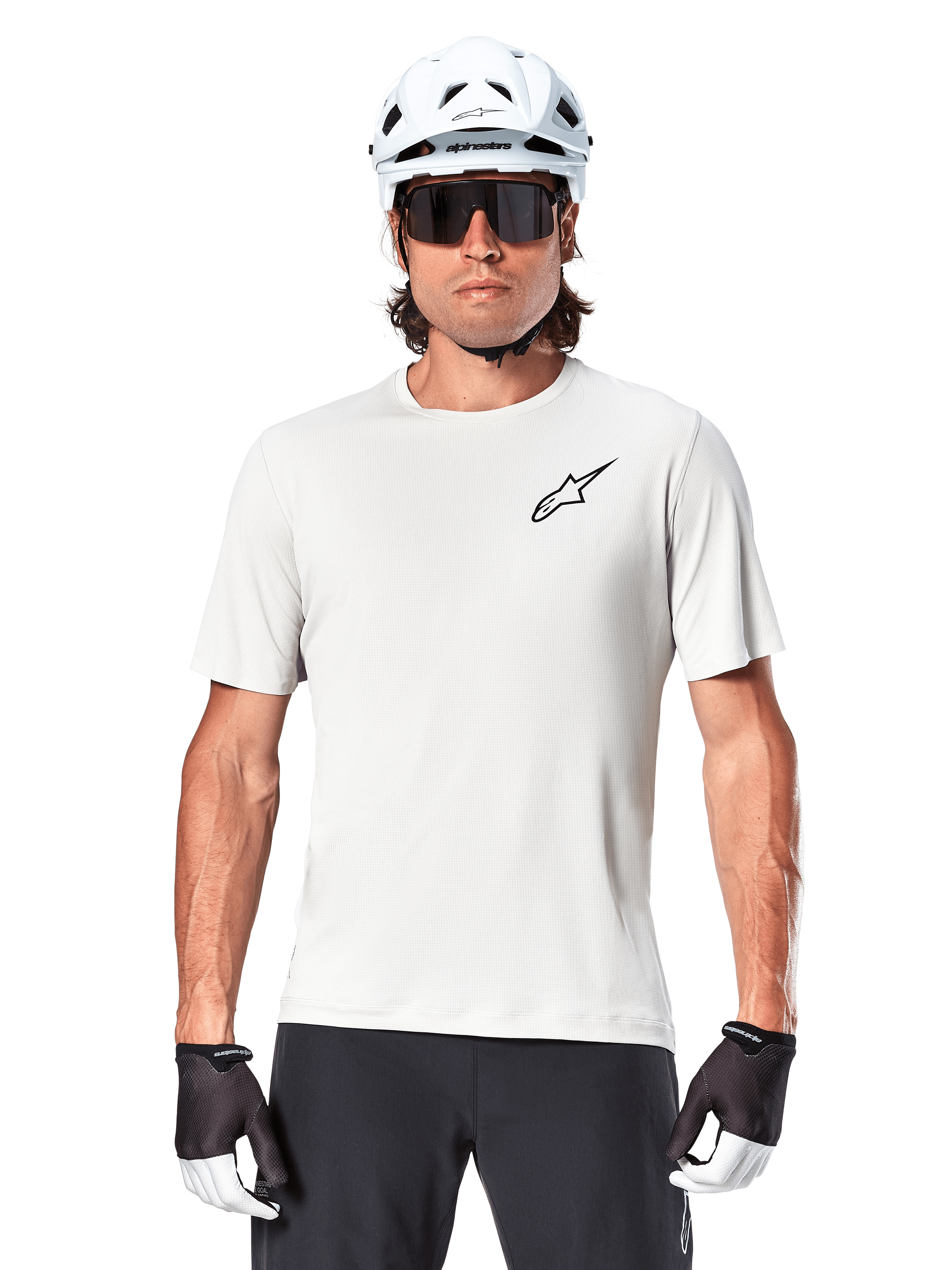 Ciclista con jersey de manga corta Alpinestars A-Aria Astar, color White Dove con pequeño logotipo Astar negro en el pecho, casco de ciclismo blanco, gafas de sol negras y guantes blancos y negros, equipamiento de alto rendimiento para MTB y conducción fuera de carretera