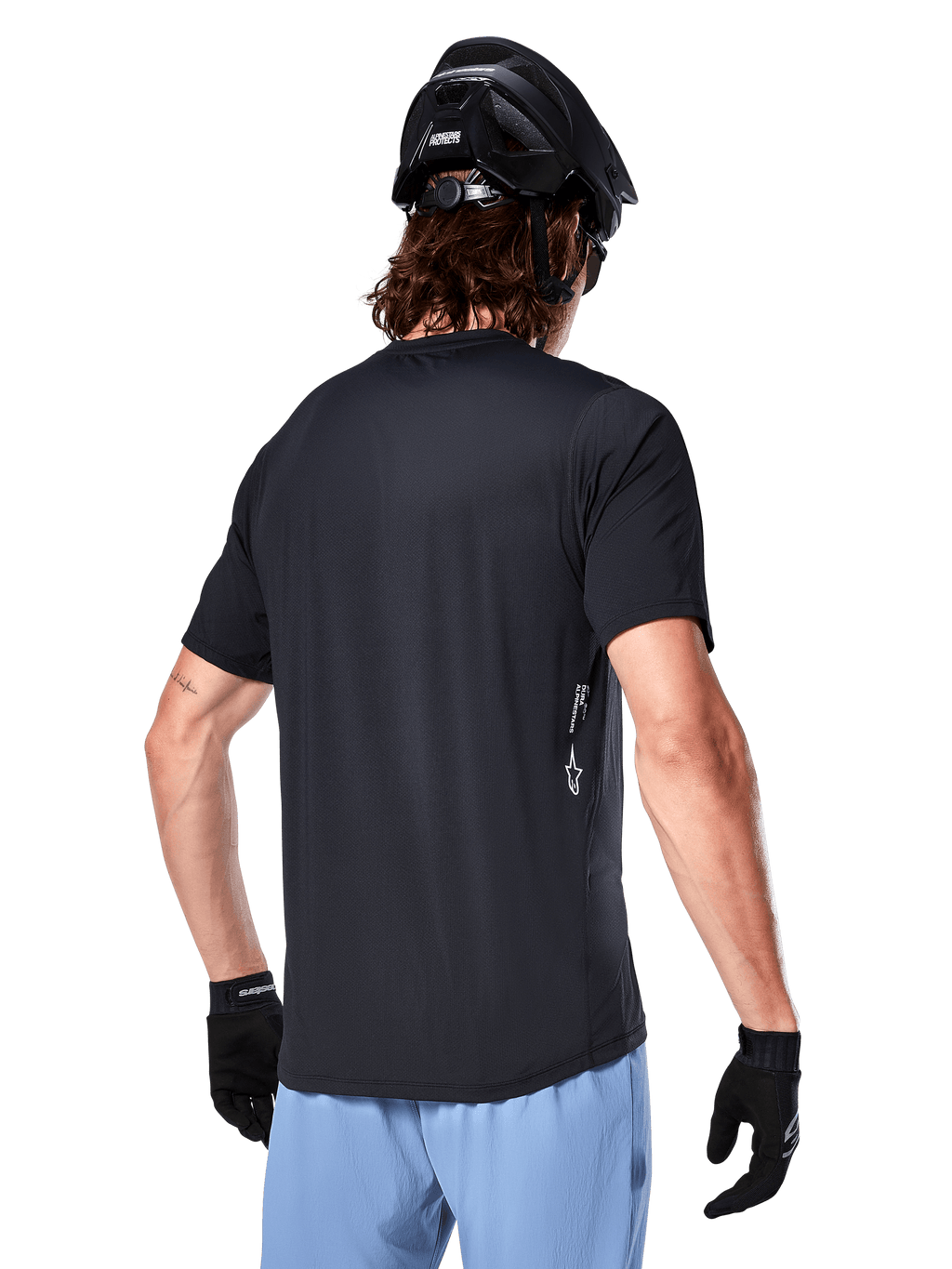Alpinestars A-Dura Oscar Jersey, jersey de ciclismo de manga corta, negro, vista trasera del ciclista, combinado con pantalones cortos azul claro y casco de MTB negro, pequeño logo blanco en el lateral, ropa técnica para ciclismo de montaña