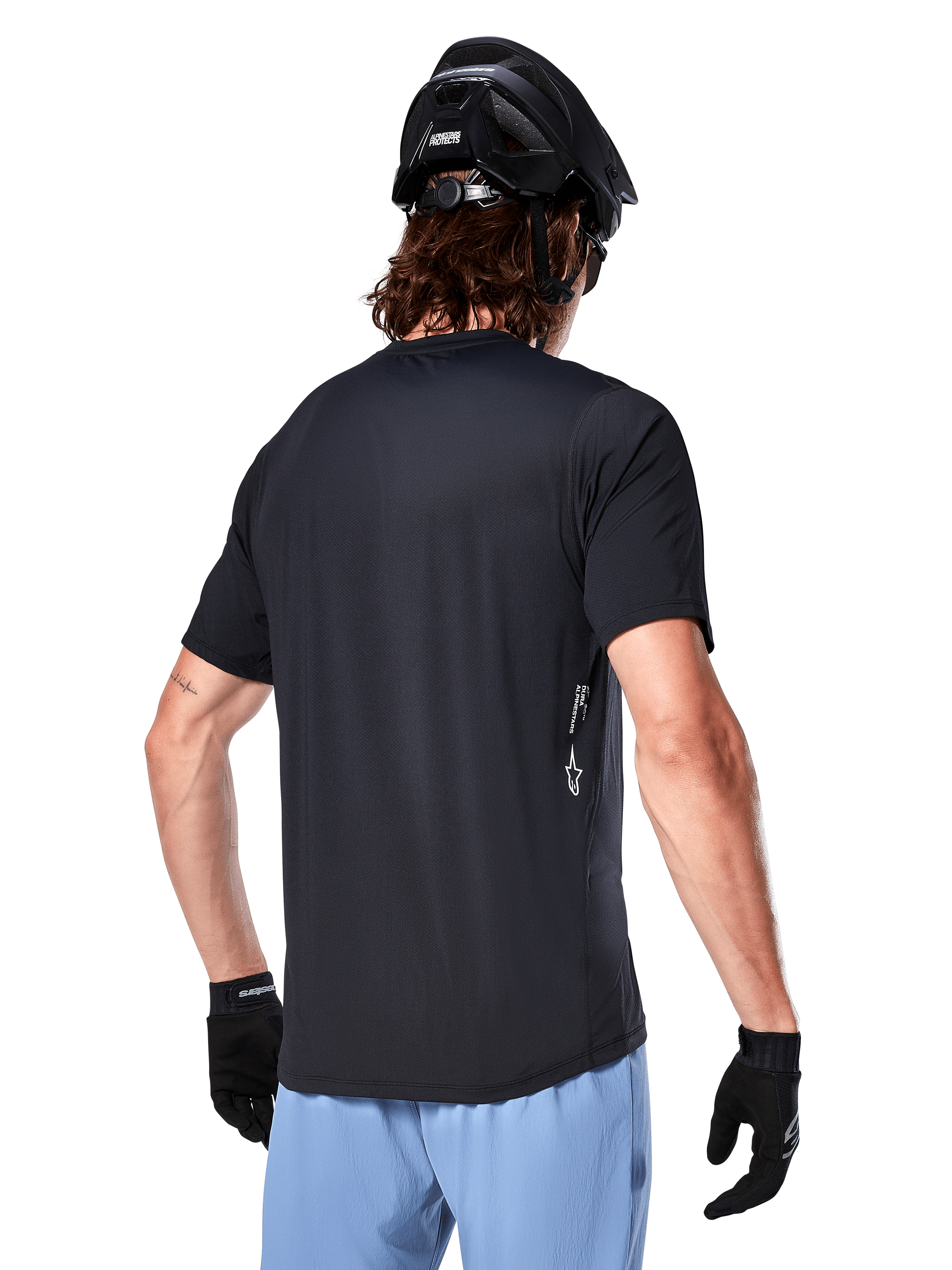 Alpinestars A-Dura Oscar Jersey, jersey de ciclismo de manga corta, negro, vista trasera del ciclista, combinado con pantalones cortos azul claro y casco de MTB negro, pequeño logo blanco en el lateral, ropa técnica para ciclismo de montaña