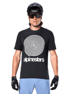 Alpinestars Jersey A-Dura Oscar, jersey de MTB de manga corta, negro, con un gran gráfico de espiral vintage de Oscar en blanco en el pecho, usado con casco de ciclismo negro, gafas de sol, guantes negros y pantalones cortos azul claro, equipamiento de ciclismo de montaña de inspiración clásica
