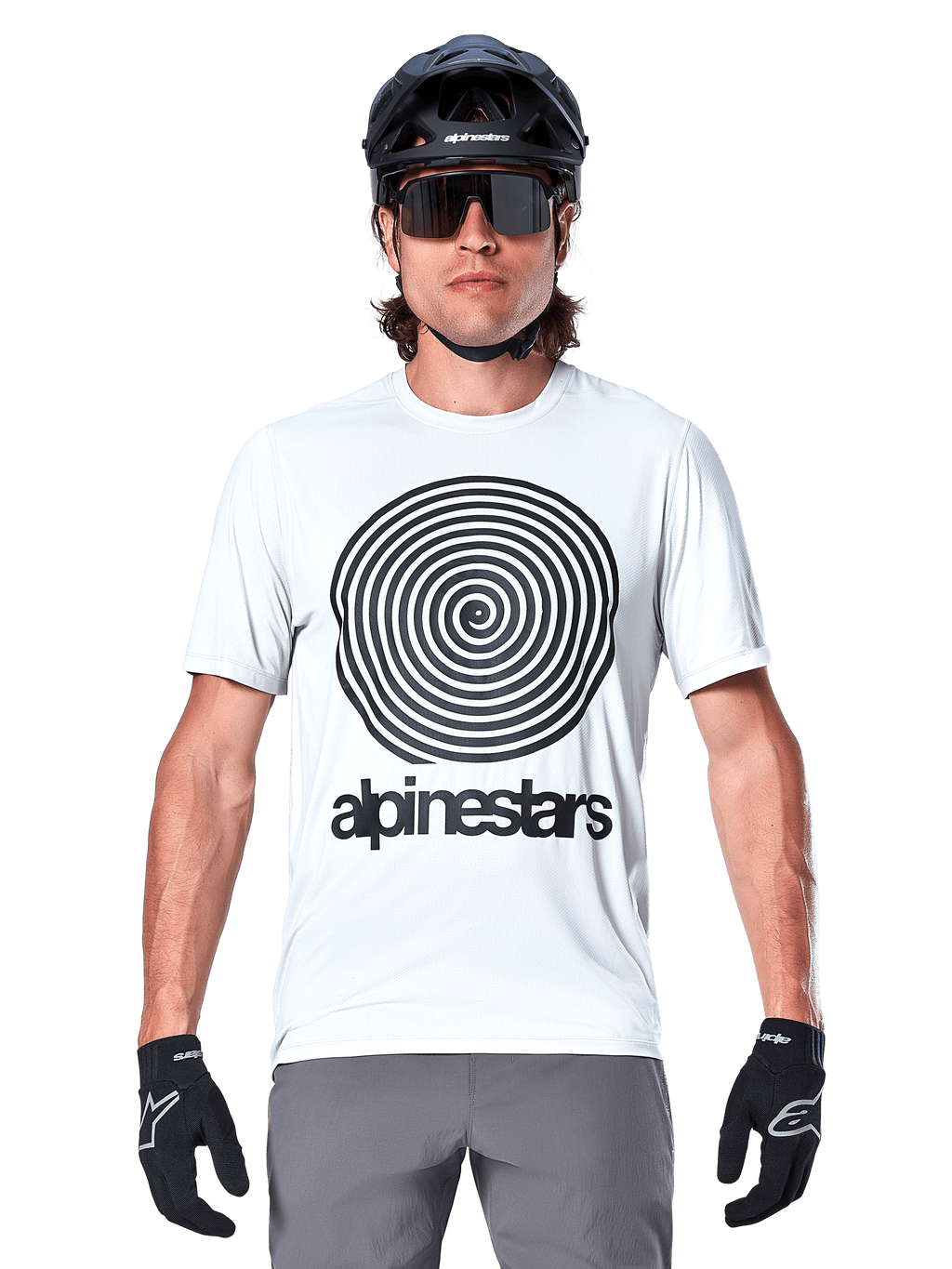 Jersey Alpinestars A-Dura Oscar de manga corta, blanco (White Dove), con un gran gráfico de espiral Oscar vintage en negro y el logotipo de Alpinestars en el pecho, usado por un modelo con casco de MTB negro, gafas de sol y guantes negros, estilo de ciclismo de herencia.