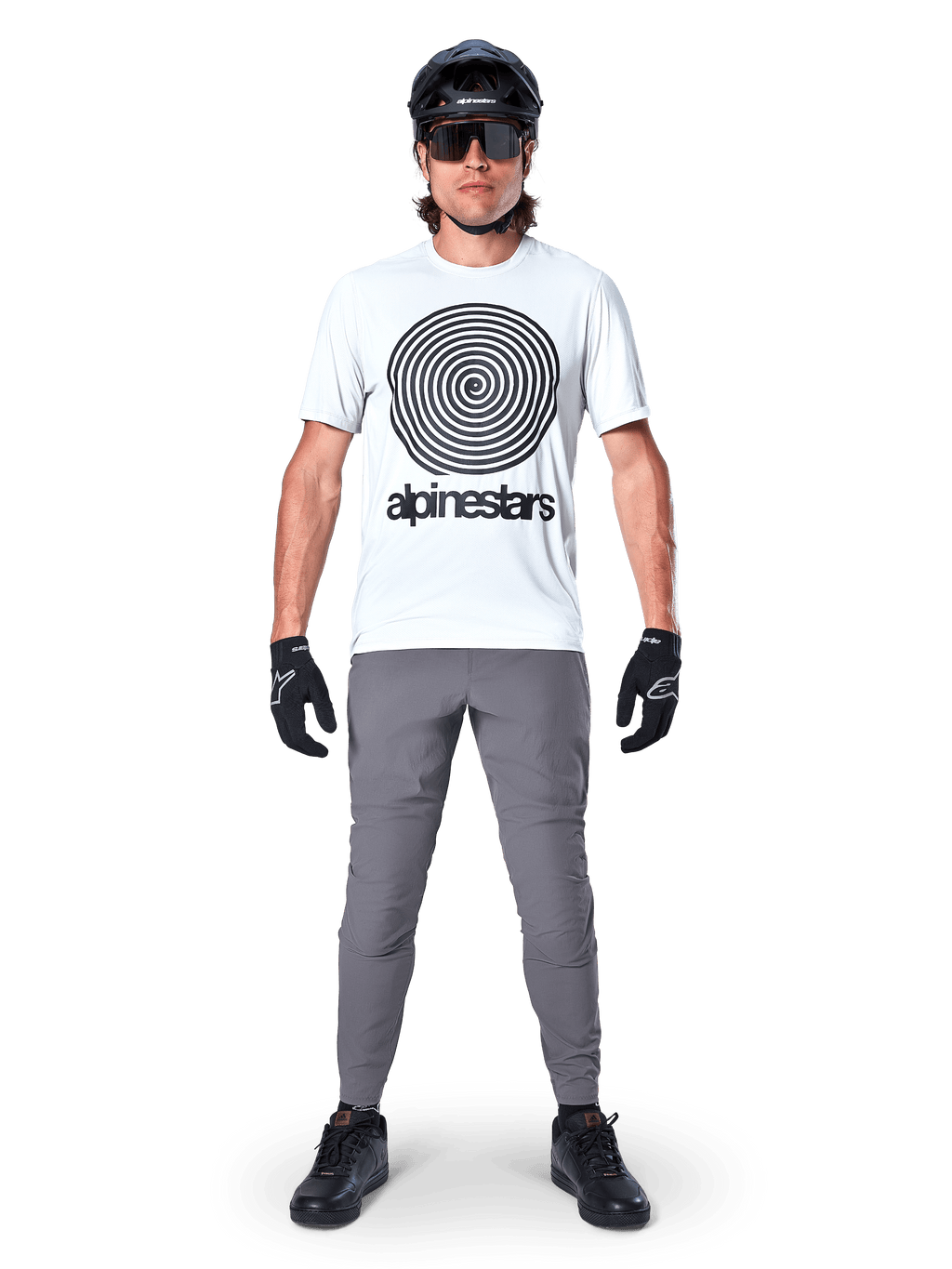 Jersey Alpinestars A-Dura Oscar de manga corta, White Dove con gran logotipo de espiral negro, combinado con pantalones grises, casco negro, gafas de sol y guantes negros, equipamiento de alto rendimiento para MTB trail
