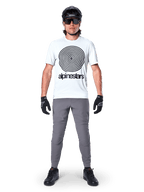 Jersey Alpinestars A-Dura Oscar de manga corta, White Dove con gran logotipo de espiral negro, combinado con pantalones grises, casco negro, gafas de sol y guantes negros, equipamiento de alto rendimiento para MTB trail