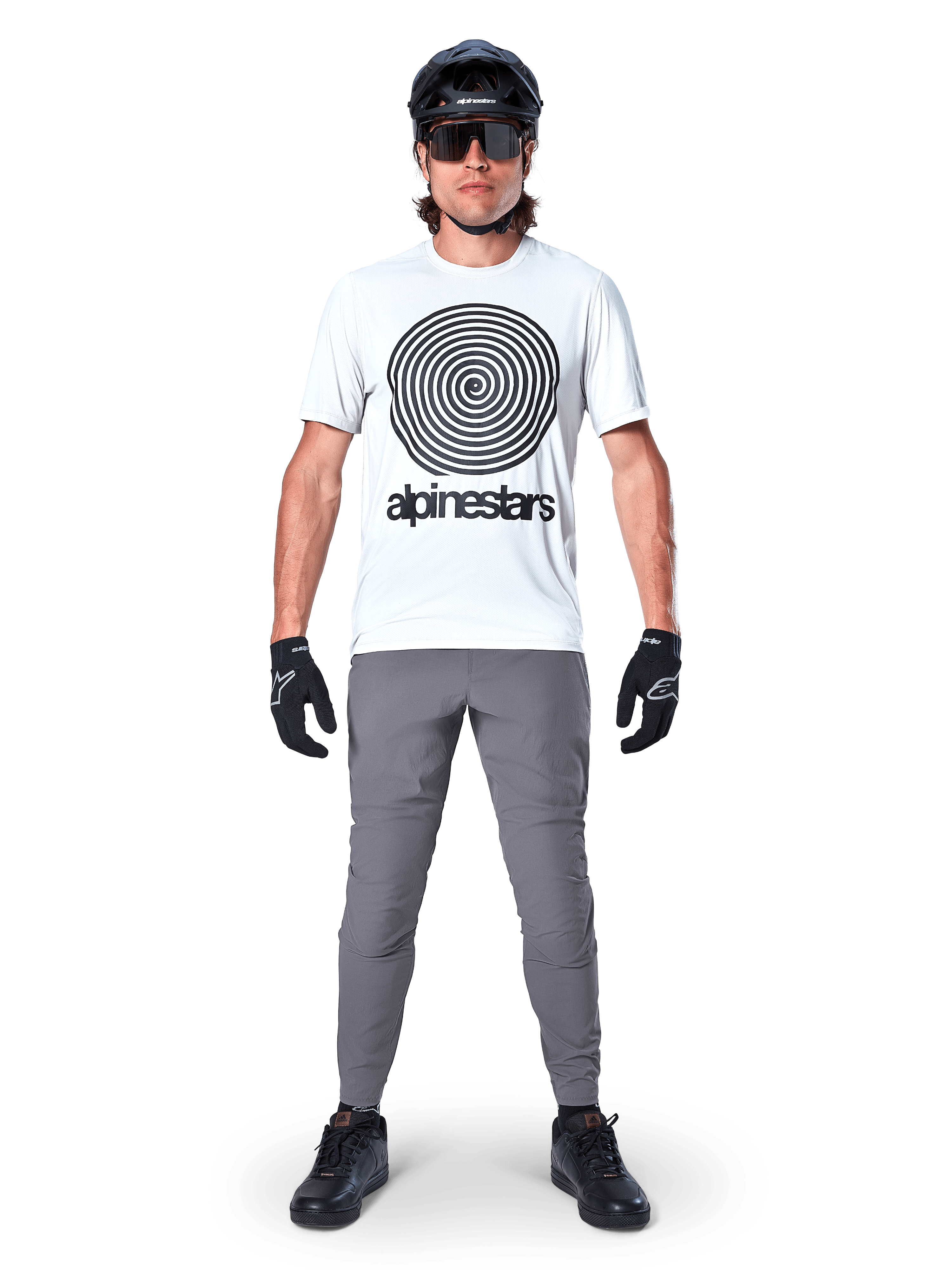Jersey Alpinestars A-Dura Oscar de manga corta, White Dove con gran logotipo de espiral negro, combinado con pantalones grises, casco negro, gafas de sol y guantes negros, equipamiento de alto rendimiento para MTB trail