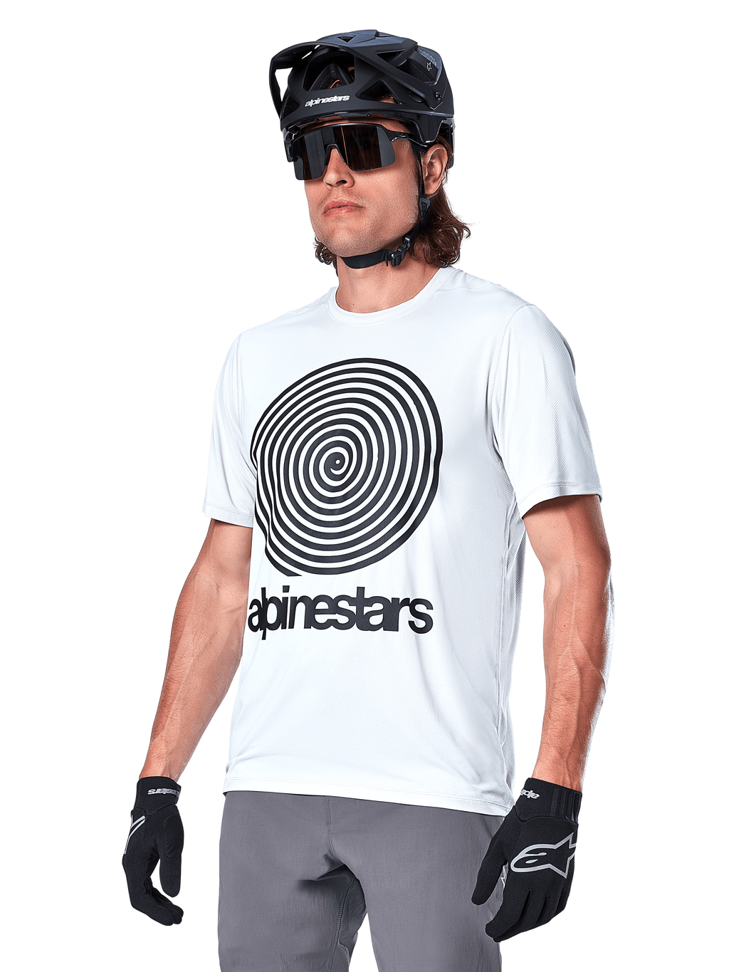 Alpinestars A-Dura Oscar Jersey de manga corta, blanco con gráfico en espiral y logotipo negro, usado con casco de MTB y guantes negros, ropa deportiva de alto rendimiento para bicicleta de montaña