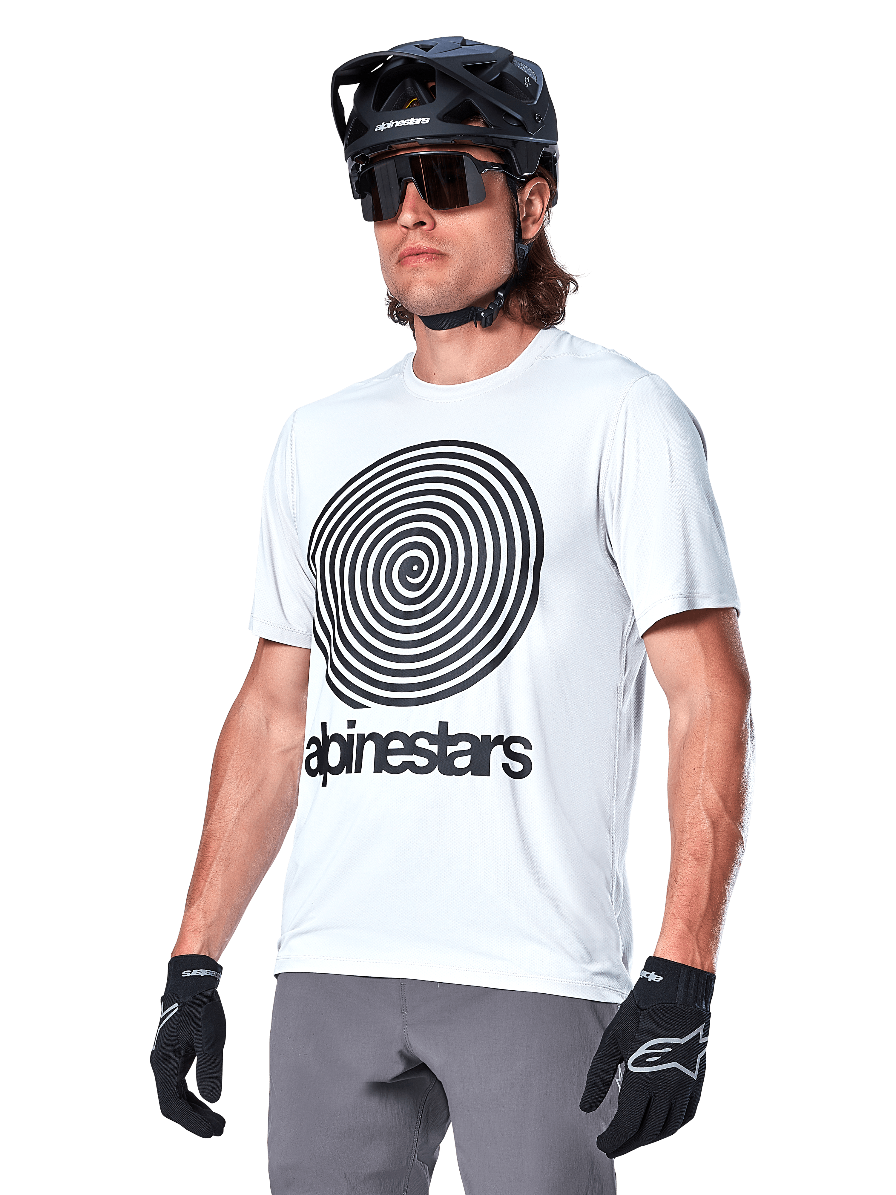 Alpinestars A-Dura Oscar Jersey de manga corta, blanco con gráfico en espiral y logotipo negro, usado con casco de MTB y guantes negros, ropa deportiva de alto rendimiento para bicicleta de montaña