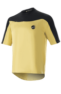 Alpinestars Drop Meta Jersey de manga corta, camiseta de ciclismo MTB, dorada y negra, construcción de malla con hombros en bloques de color, logo circular en el pecho y dobladillo trasero extendido.
