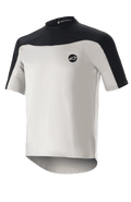 Alpinestars Drop Meta Jersey de manga corta, jersey de ciclismo de montaña, gris claro y negro, con una construcción de malla transpirable, canesú negro en los hombros, cuello redondo y parte trasera extendida para mayor cobertura.
