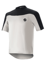 Alpinestars Drop Meta Jersey de manga corta, jersey de ciclismo de montaña, gris claro y negro, con una construcción de malla transpirable, canesú negro en los hombros, cuello redondo y parte trasera extendida para mayor cobertura.