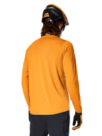 Alpinestars Jersey de manga larga A-Dura Rocker, Oro Oscuro, vista posterior del ciclista con casco de MTB negro y naranja, pantalones oscuros y guantes a juego, ropa de ciclismo de montaña de rendimiento casual