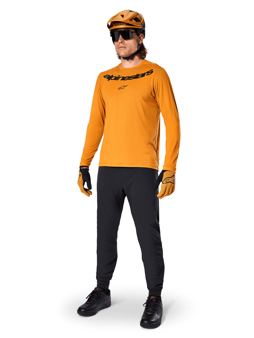 Alpinestars A-Dura Rocker Long Sleeve Jersey, jersey de ciclismo en color Dark Gold, usado con casco de MTB a juego y pantalones negros, con logotipo de la marca negro en el pecho, equipamiento de alto rendimiento para ciclismo de montaña todoterreno