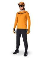 Alpinestars A-Dura Rocker Long Sleeve Jersey, jersey de ciclismo en color Dark Gold, usado con casco de MTB a juego y pantalones negros, con logotipo de la marca negro en el pecho, equipamiento de alto rendimiento para ciclismo de montaña todoterreno