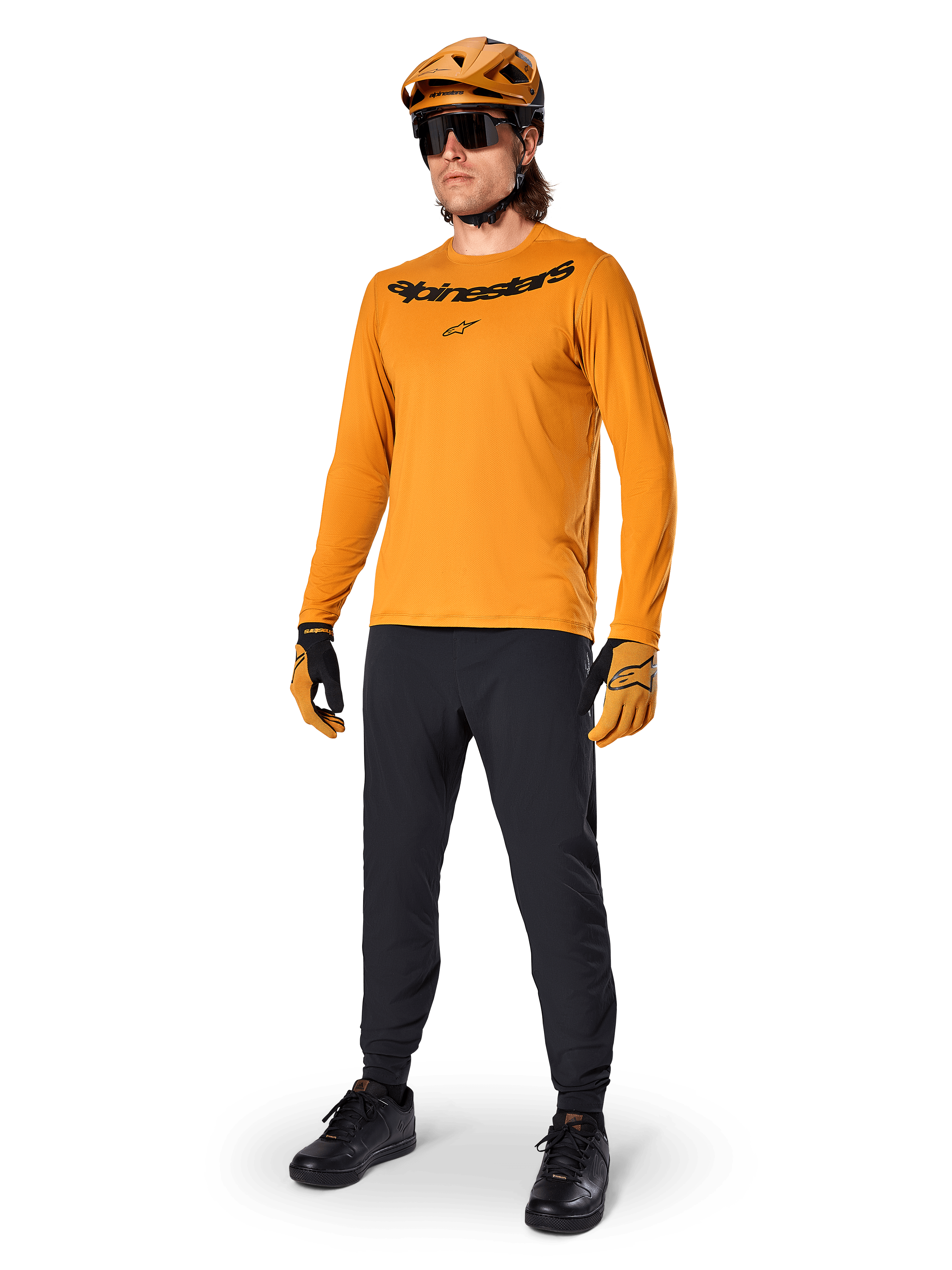 Alpinestars A-Dura Rocker Long Sleeve Jersey, jersey de ciclismo en color Dark Gold, usado con casco de MTB a juego y pantalones negros, con logotipo de la marca negro en el pecho, equipamiento de alto rendimiento para ciclismo de montaña todoterreno