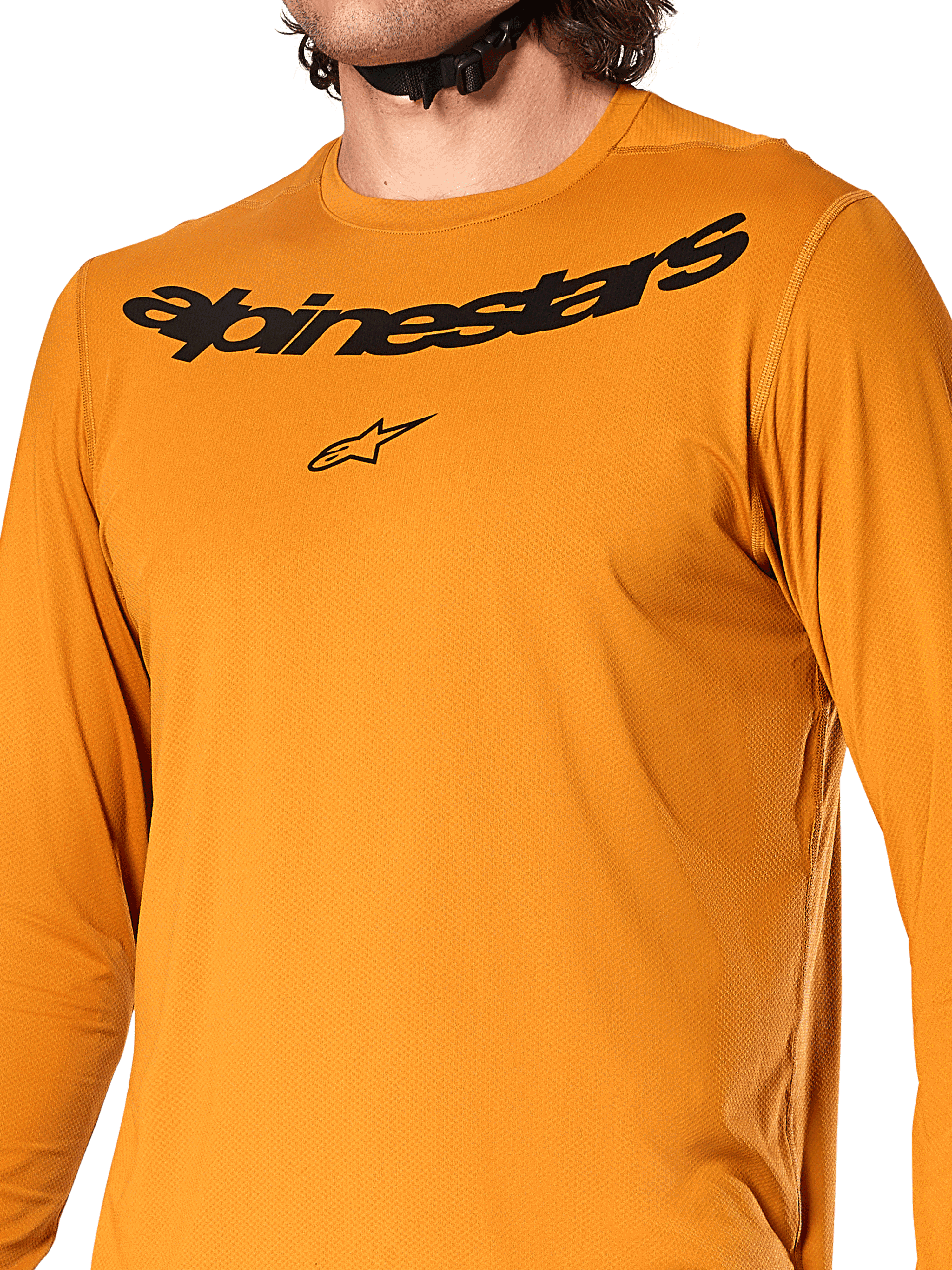 Camiseta de manga larga Alpinestars A-Dura Rocker, color Dark Gold, vista de primer plano del pecho con el logotipo y la marca Alpinestars en negro, tejido jacquard texturizado que absorbe la humedad, ropa técnica para ciclismo de montaña MTB