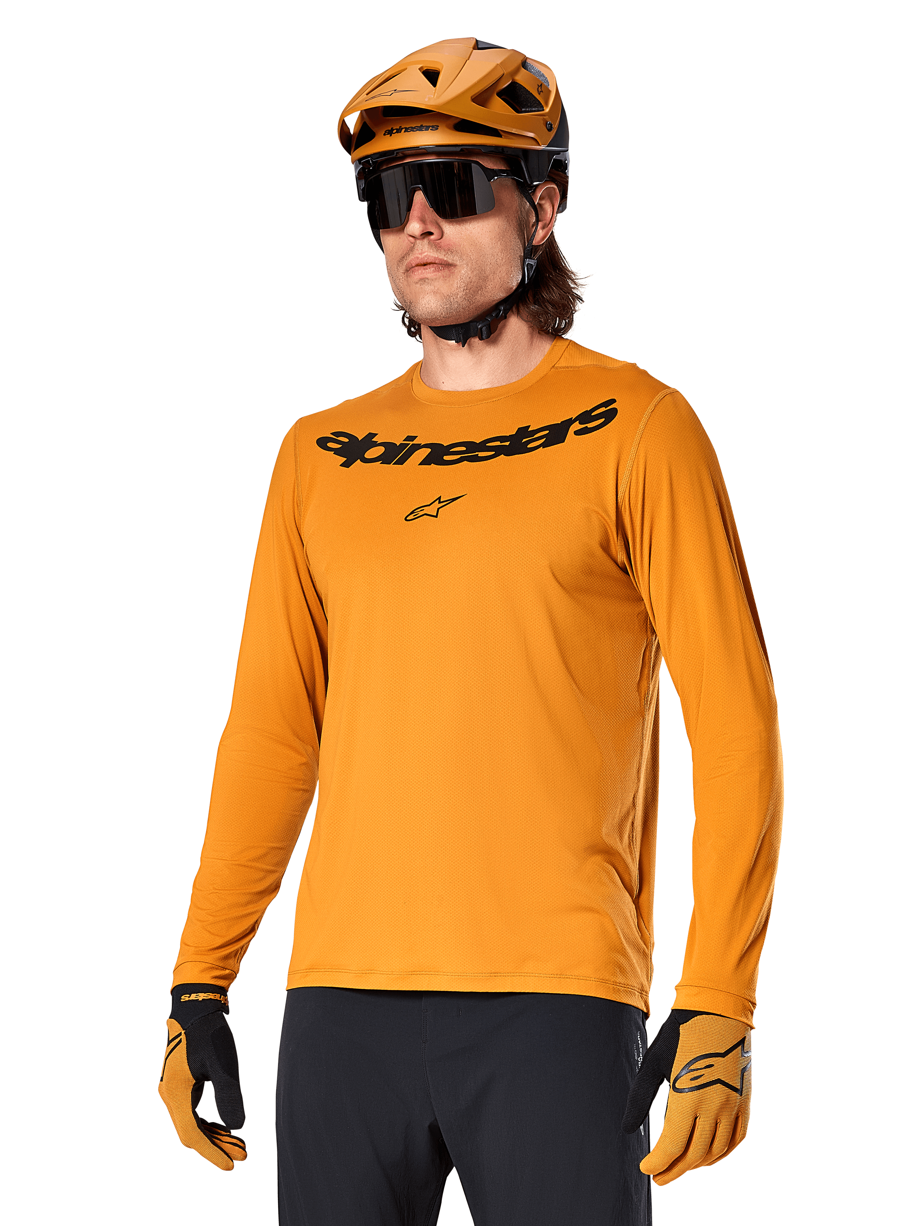 Alpinestars A-Dura Rocker Jersey de manga larga, camiseta para ciclismo de montaña MTB, color oro oscuro, persona con jersey, casco y guantes a juego, look deportivo coordinado con el logotipo de Alpinestars en el pecho