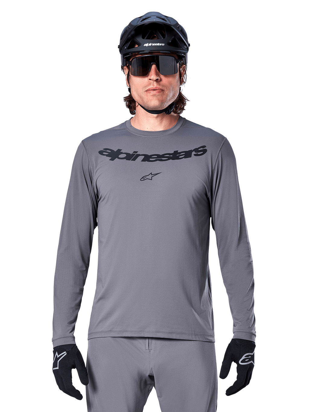 Alpinestars A-Dura Rocker Long Sleeve Jersey, jersey de MTB para hombre en gris oscuro con logotipo negro en el pecho, combinado con pantalones grises, casco negro y guantes, diseñado para ciclismo de montaña