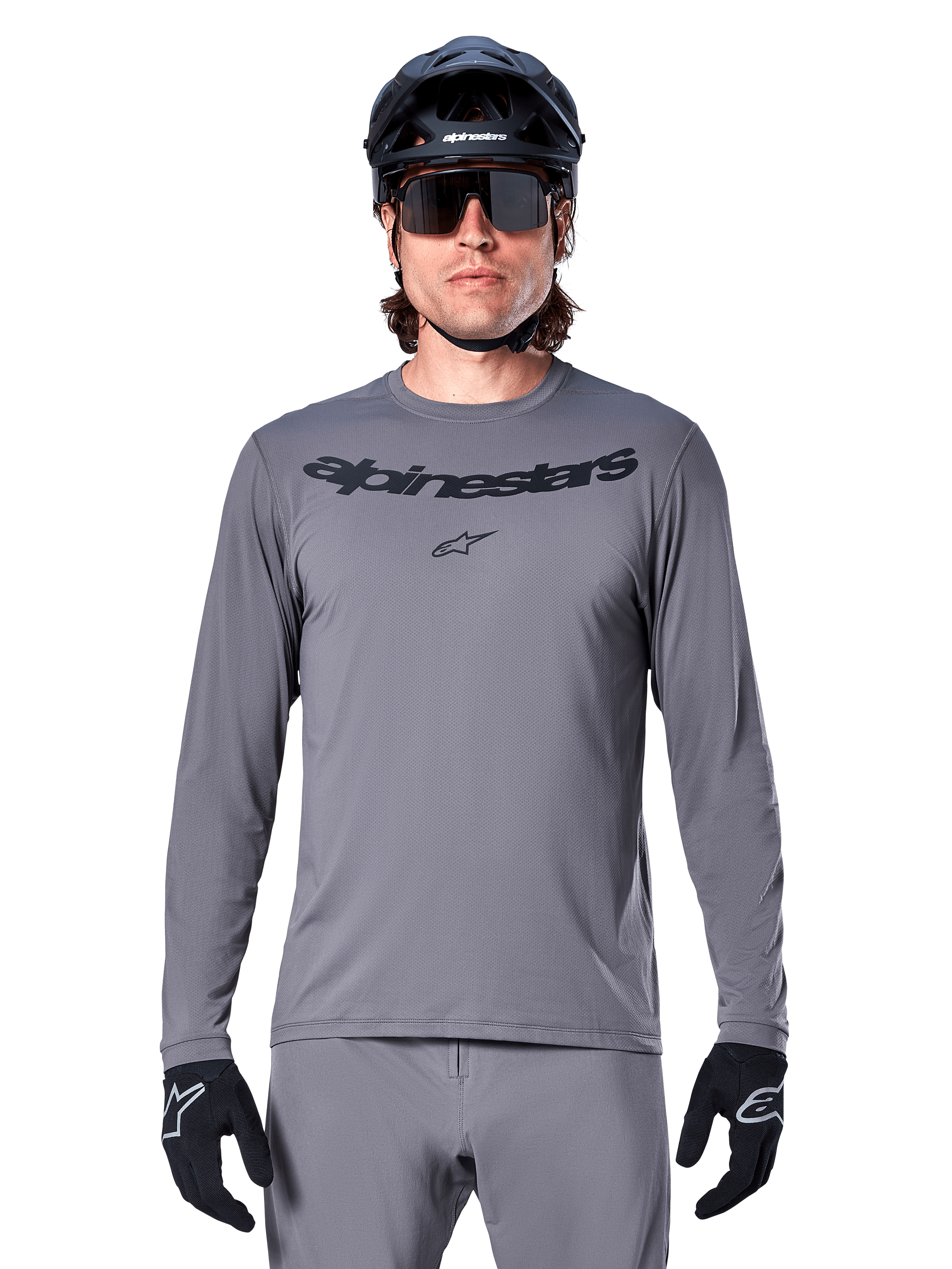 Alpinestars A-Dura Rocker Long Sleeve Jersey, jersey de MTB para hombre en gris oscuro con logotipo negro en el pecho, combinado con pantalones grises, casco negro y guantes, diseñado para ciclismo de montaña