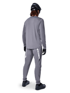 Jersey de manga larga Alpinestars A-Dura Rocker, gris oscuro, vista trasera del modelo luciendo pantalones de MTB grises a juego, casco negro y guantes negros, diseño de ropa profesional para bicicleta de montaña