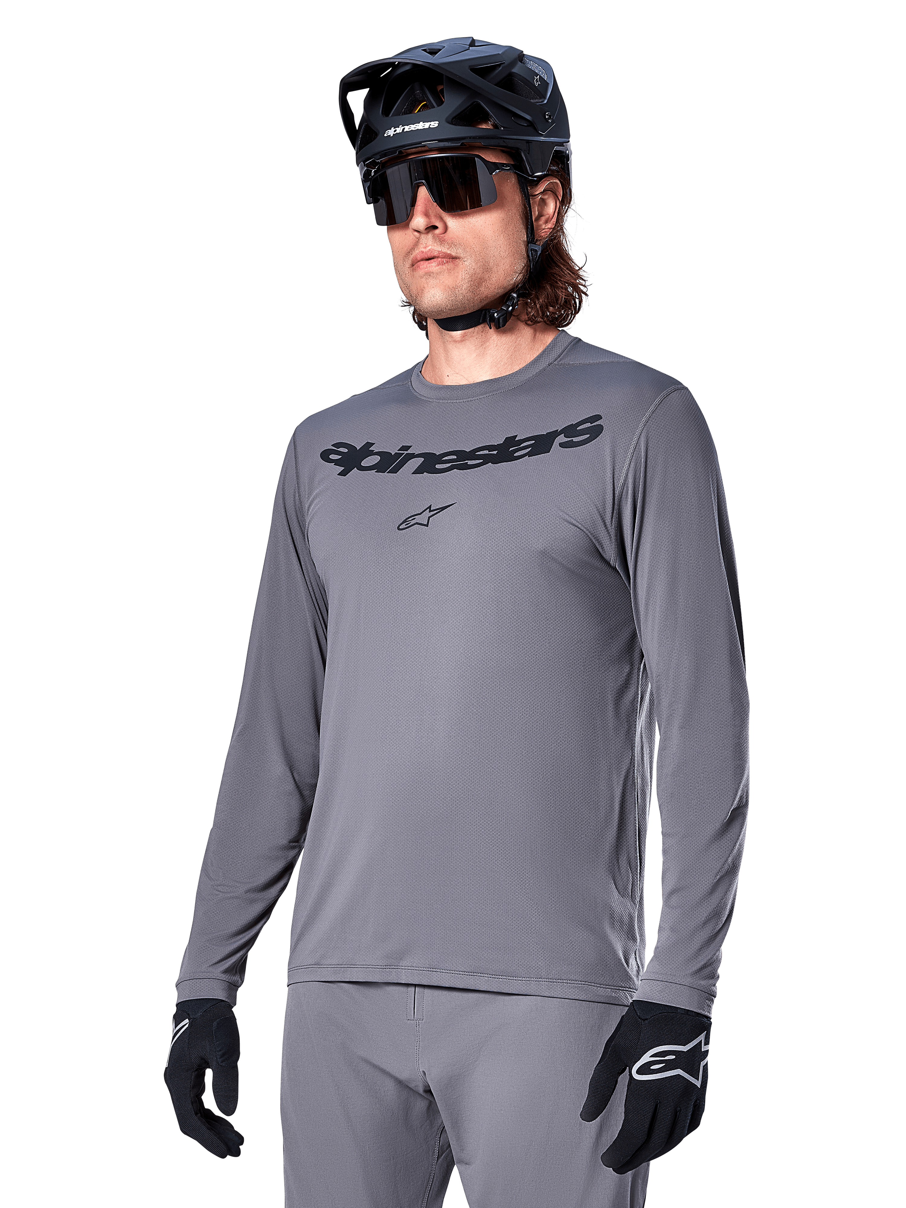 Alpinestars A-Dura Rocker Jersey de manga larga, jersey de MTB gris para ciclismo de montaña, usado con casco y guantes negros, con logotipo negro en el pecho, ropa deportiva de ciclismo para recorridos todoterreno, fondo liso
