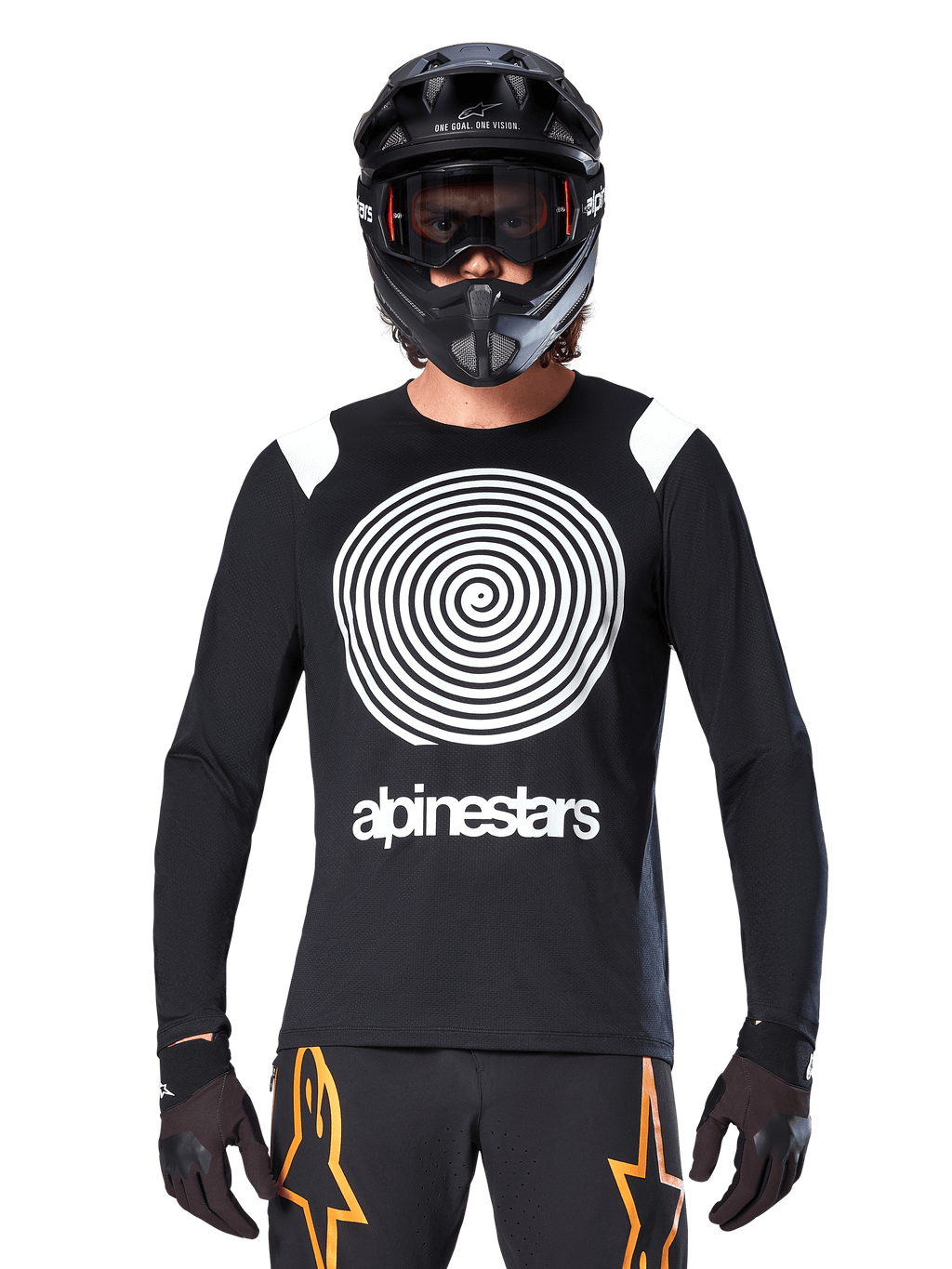 Jersey de manga larga Alpinestars A-Supra Oscar, negro con gráfico en espiral blanco y detalles en los hombros, usado por un ciclista con casco integral negro y gafas, pantalones negros y naranjas, equipamiento técnico de ciclismo para MTB de gravedad