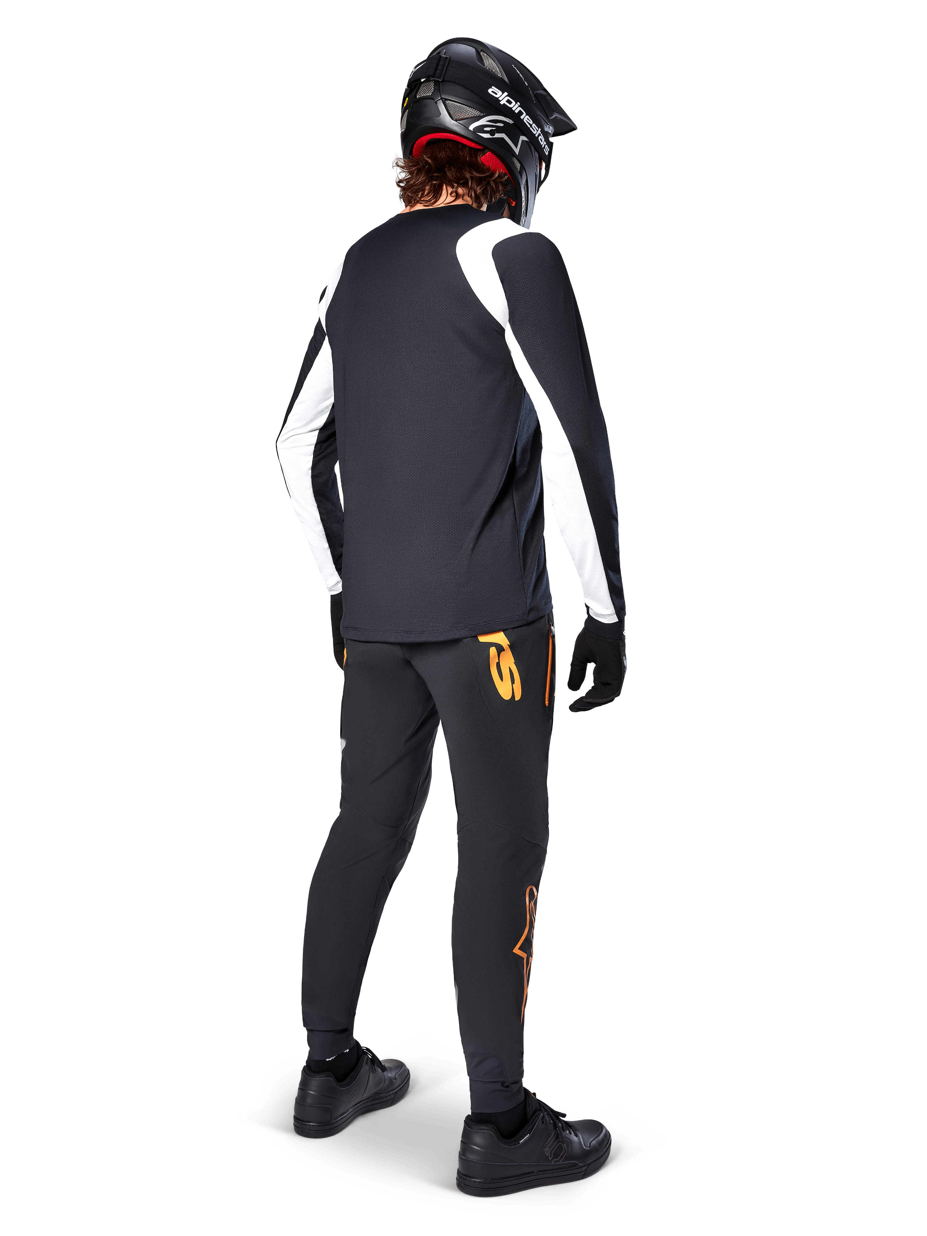 Jersey de manga larga Alpinestars A-Supra Oscar, negro con paneles blancos en las mangas, visto desde atrás en un ciclista de MTB con casco integral negro y pantalones negros con logotipos naranjas, ropa de ciclismo para gravity todoterreno