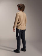 Alpinestars A-Dura Astar Long Sleeve Jersey in Light Brown, back view of a male model showcasing the drop tail design, paired with black pants and shoes, casual mountain bike performance gear.