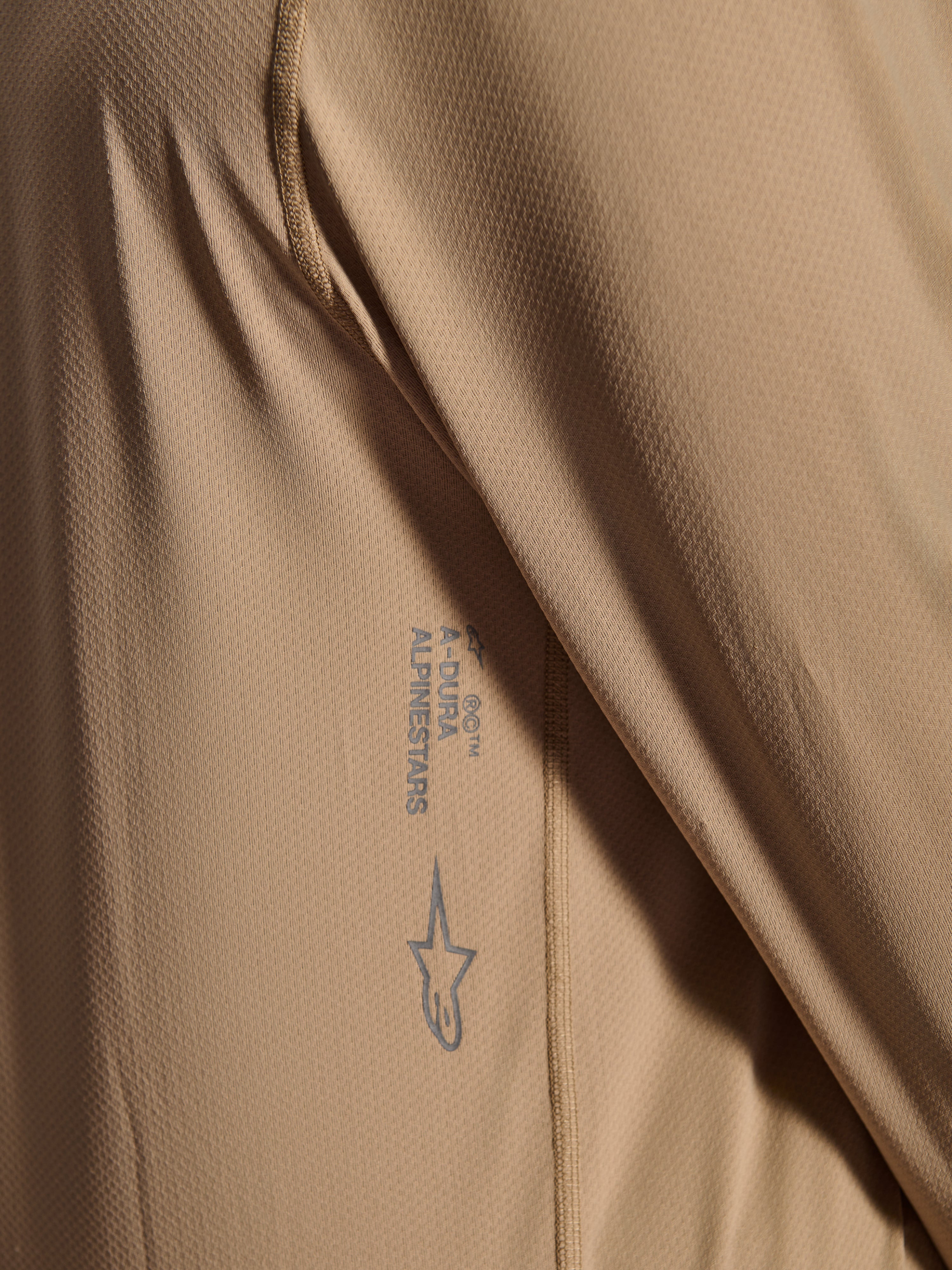 Alpinestars A-Dura Astar Long Sleeve Jersey, MTB Cycling Jersey, Brown, Close-up showing jacquard fabric texture, printed Astars logo and A-Dura wordmark, technical mountain bike apparel