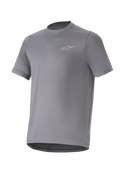 Alpinestars A-Dura Astar Jersey, camiseta de manga corta para ciclismo de montaña, gris oscuro con un pequeño logotipo plateado en el pecho, cuello redondo y parte trasera extendida, tejido técnico transpirable para rutas de MTB