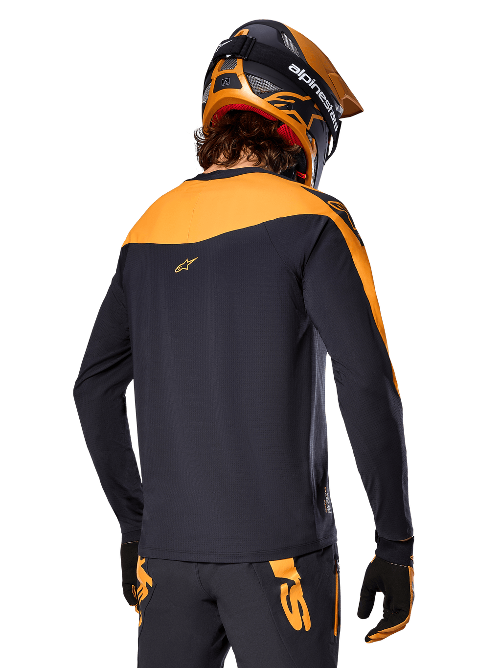 Alpinestars A-Supra Race Jersey de manga larga, negro y naranja, vista trasera del piloto con casco y pantalones de montaña a juego, ajuste de rendimiento con textura microperforada, equipo profesional para carreras de MTB