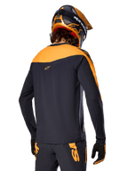Alpinestars A-Supra Race Jersey de manga larga, negro y naranja, vista trasera del piloto con casco y pantalones de montaña a juego, ajuste de rendimiento con textura microperforada, equipo profesional para carreras de MTB