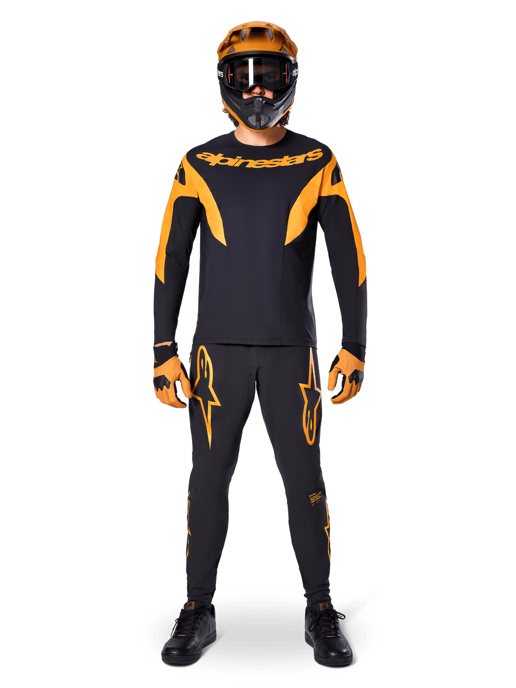 Ciclista de MTB con el Jersey Alpinestars A-Supra Race de manga larga en negro y naranja, pantalones, guantes y casco integral con gafas a juego, conjunto coordinado de ciclismo de montaña para competición y rendimiento off-road