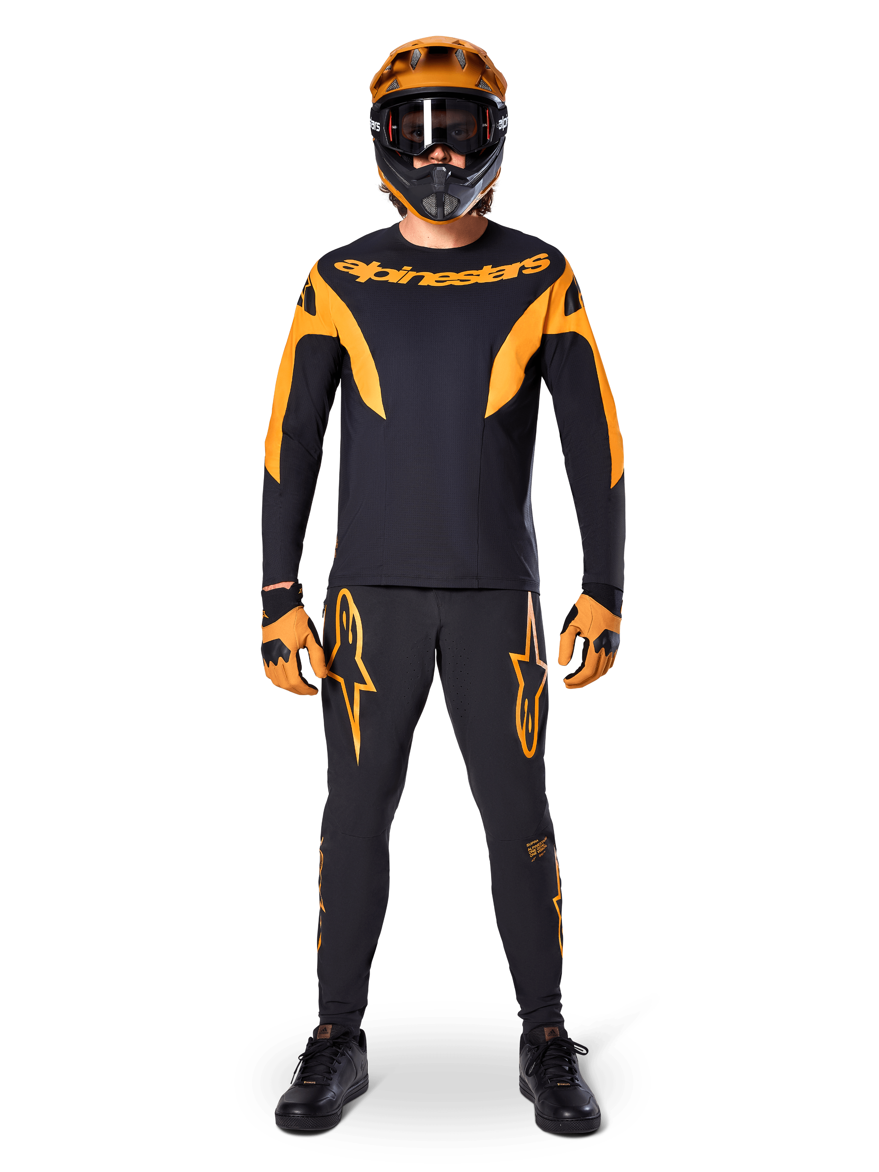Ciclista de MTB con el Jersey Alpinestars A-Supra Race de manga larga en negro y naranja, pantalones, guantes y casco integral con gafas a juego, conjunto coordinado de ciclismo de montaña para competición y rendimiento off-road