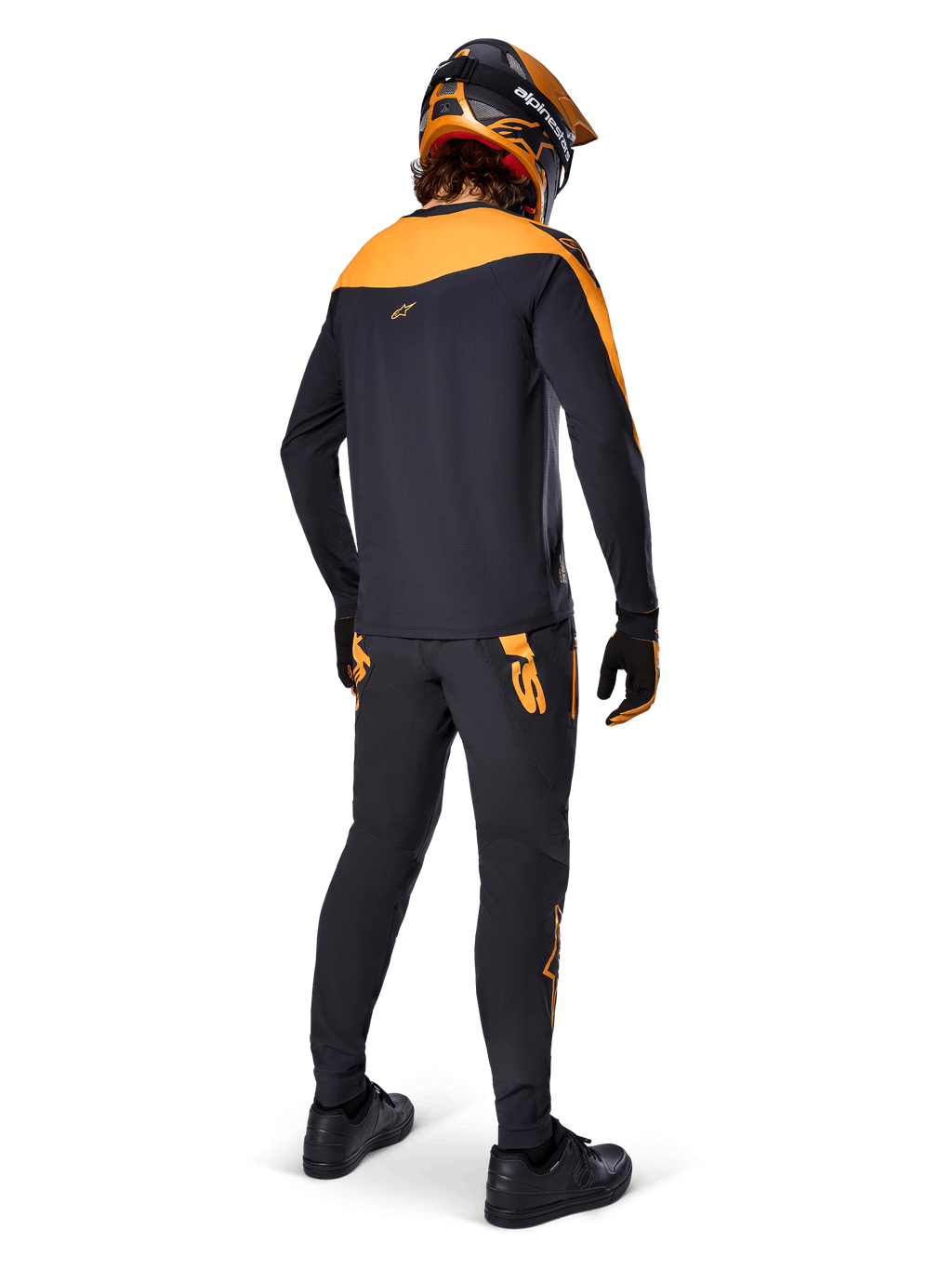 Jersey A-Supra Race de manga larga, negro y naranja, vista trasera de un piloto con pantalones de MTB a juego, casco naranja y negro, y guantes, equipamiento de alto rendimiento para carreras de mountain bike