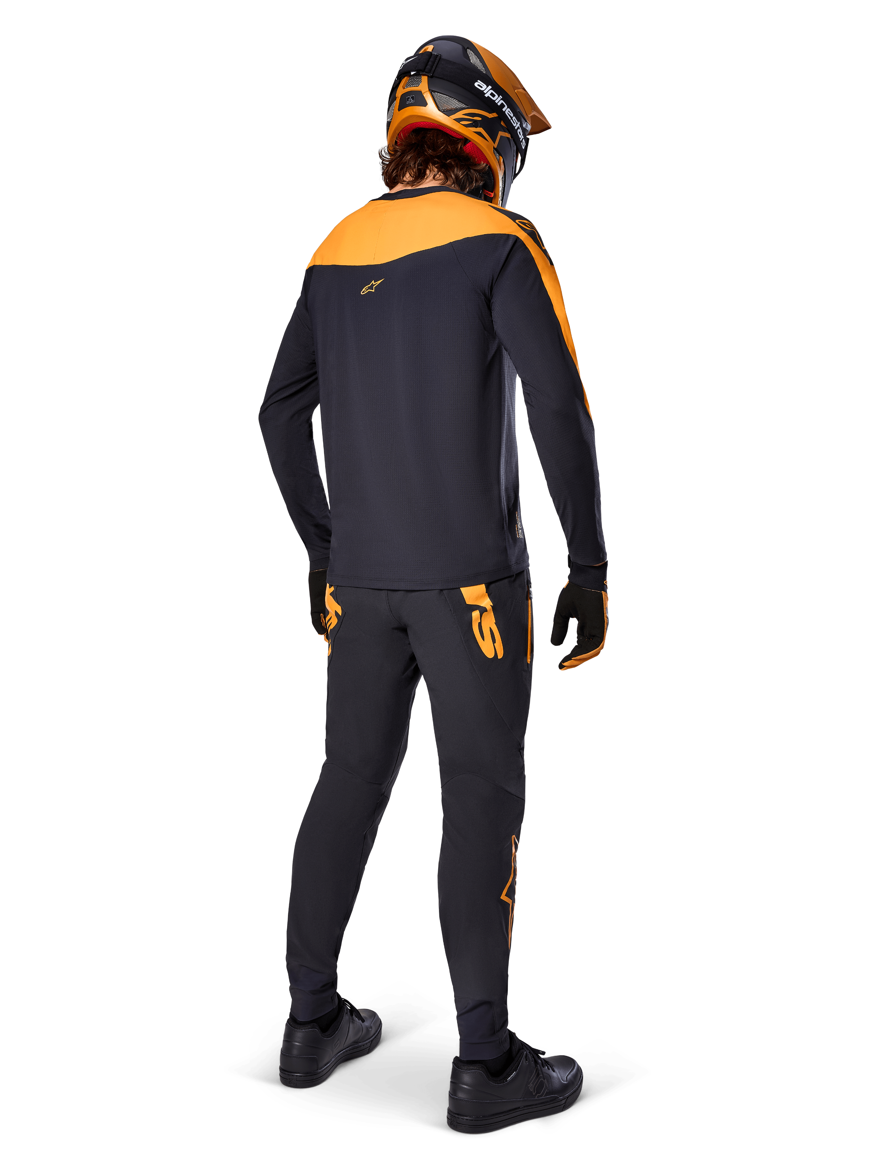 Jersey A-Supra Race de manga larga, negro y naranja, vista trasera de un piloto con pantalones de MTB a juego, casco naranja y negro, y guantes, equipamiento de alto rendimiento para carreras de mountain bike