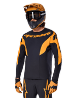Alpinestars A-Supra Race Jersey de manga larga, camiseta de ciclismo MTB, negra y naranja, combinada con casco y guantes a juego, con el logotipo de Alpinestars en el pecho y detalles estilizados en las mangas, ajuste de rendimiento para carreras off-road