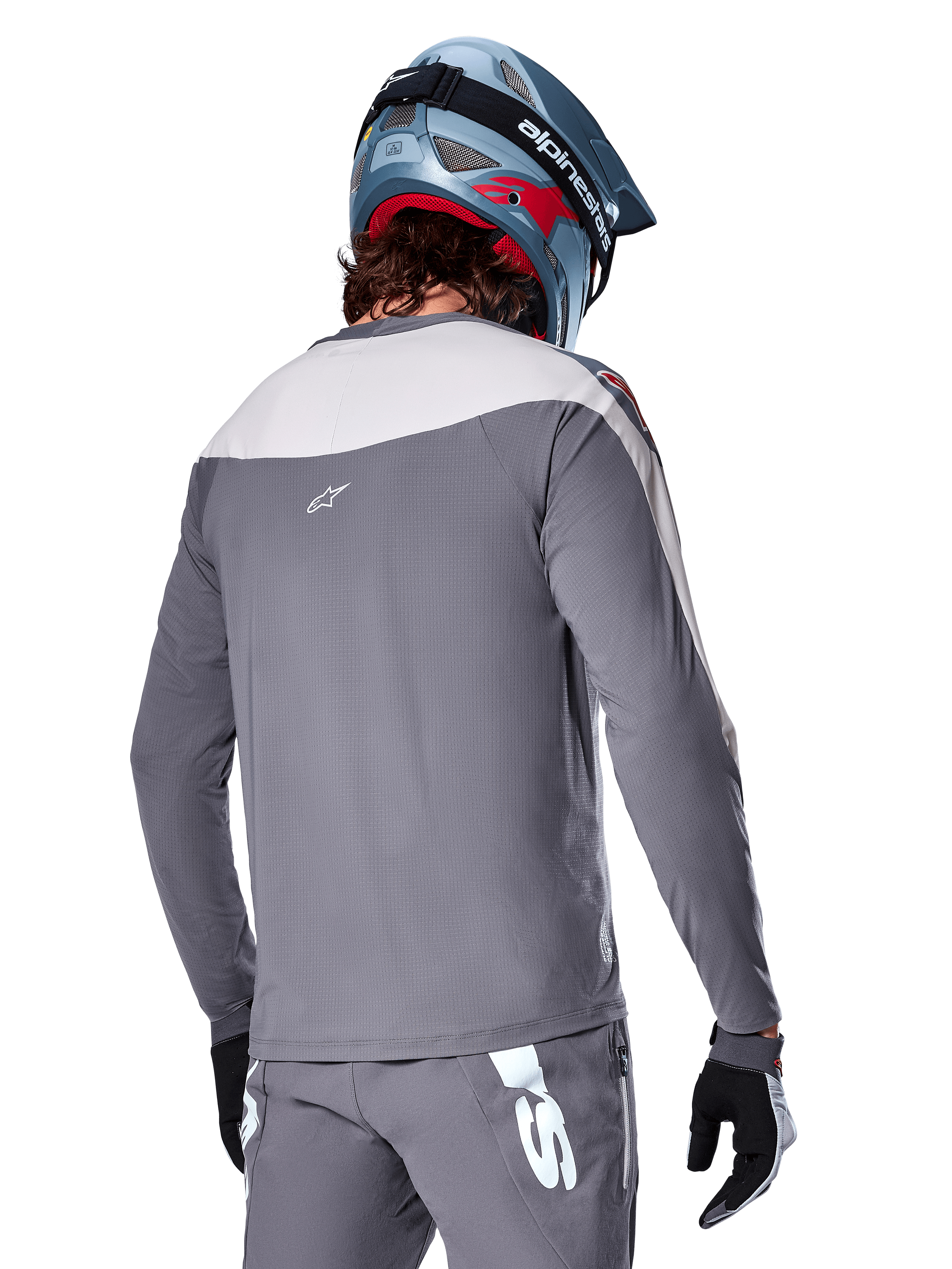 Alpinestars A-Supra Race Jersey, jersey de MTB de manga larga en gris oscuro y gris claro, vista posterior que muestra el ajuste de rendimiento y el logotipo Astar, usado con pantalones grises a juego y un casco azul de bicicleta de montaña, diseñado para ciclismo de montaña.