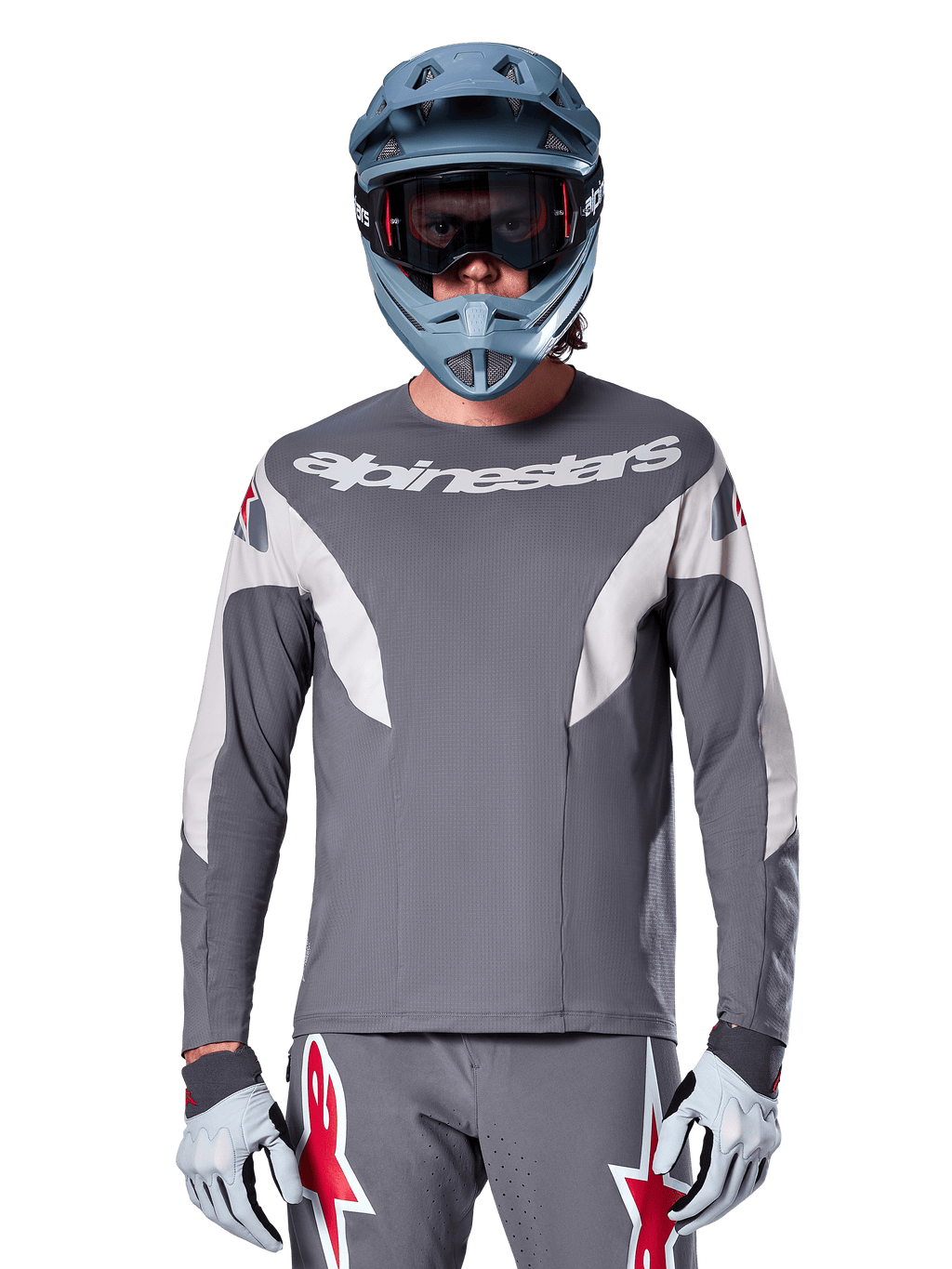 Ciclista de MTB vistiendo el Jersey Alpinestars A-Supra Race - Manga Larga en gris oscuro, jersey de ciclismo de manga larga con marca Alpinestars en blanco, combinado con un casco integral gris azulado, gafas y guantes de carreras grises, equipo completo de carreras de bicicleta de montaña para rendimiento todoterreno