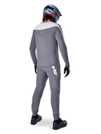 Alpinestars A-Supra Race Jersey, jersey de MTB de manga larga, gris oscuro con panel gris claro en los hombros, vista posterior usado con pantalones a juego, casco integral azul y rojo, guantes y zapatillas negros, equipamiento de ciclismo de alto rendimiento inspirado en la competición