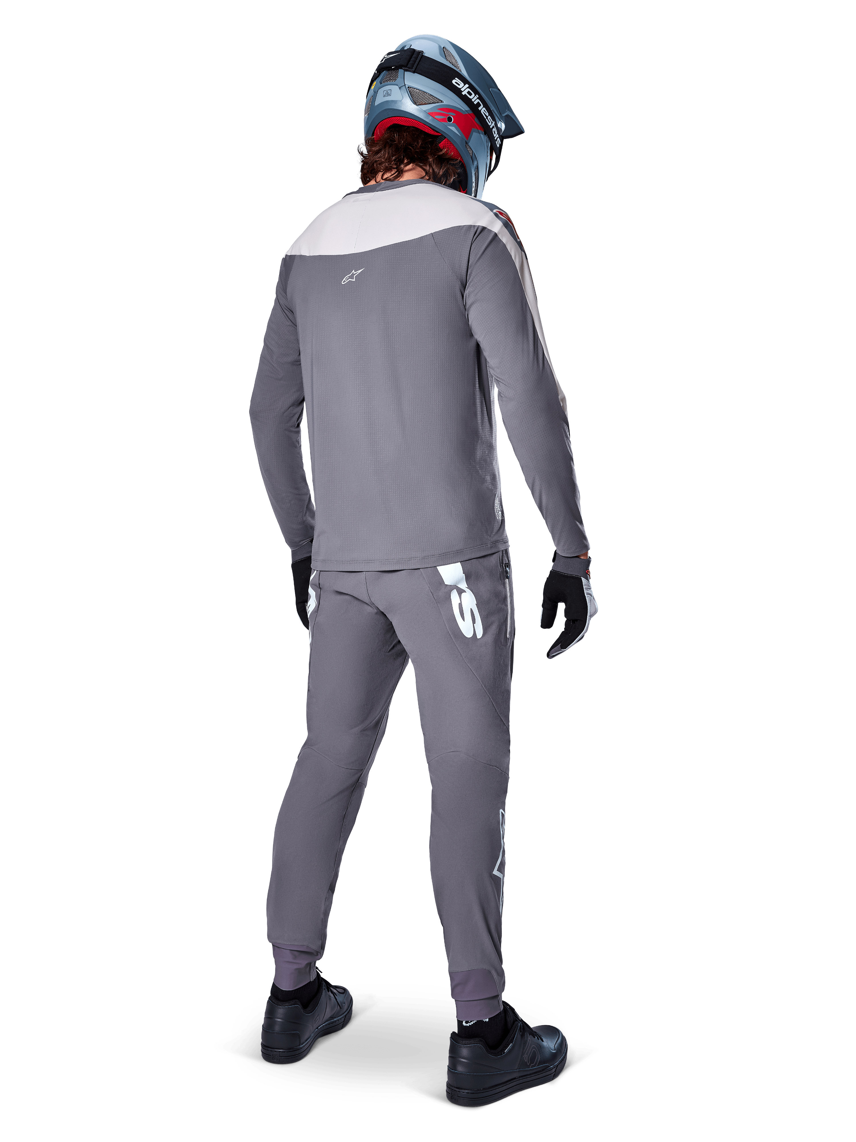 Alpinestars A-Supra Race Jersey, jersey de MTB de manga larga, gris oscuro con panel gris claro en los hombros, vista posterior usado con pantalones a juego, casco integral azul y rojo, guantes y zapatillas negros, equipamiento de ciclismo de alto rendimiento inspirado en la competición