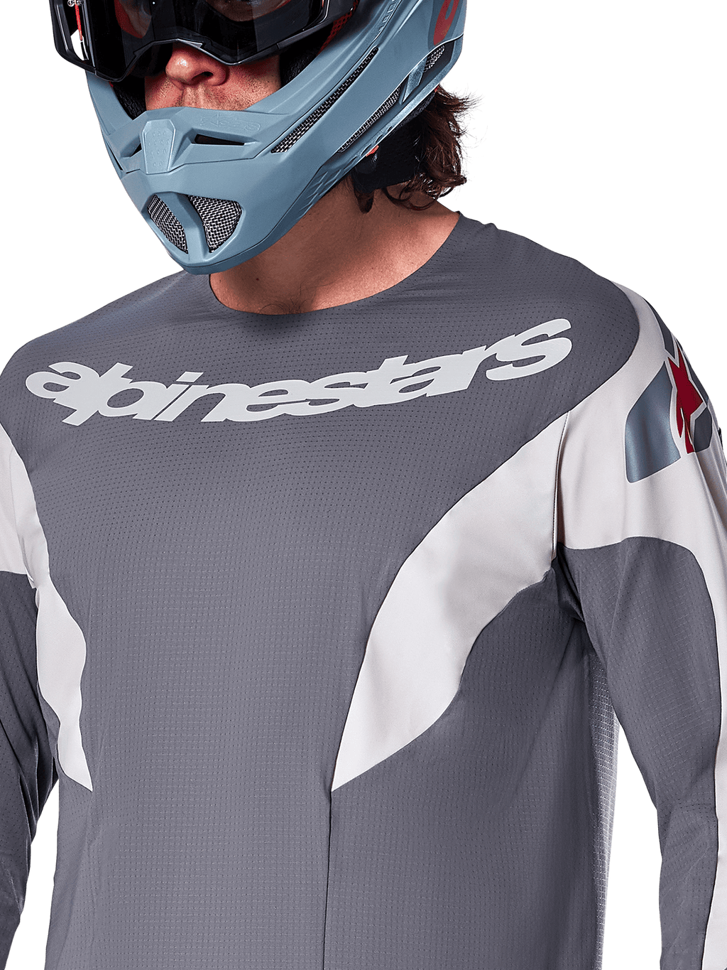 Alpinestars A-Supra Race Jersey - Manga Larga, jersey de MTB, gris oscuro con gráficos de carreras blancos y logotipo de Alpinestars blanco, usado con casco integral azul claro y gafas, tejido microperforado para rendimiento todoterreno