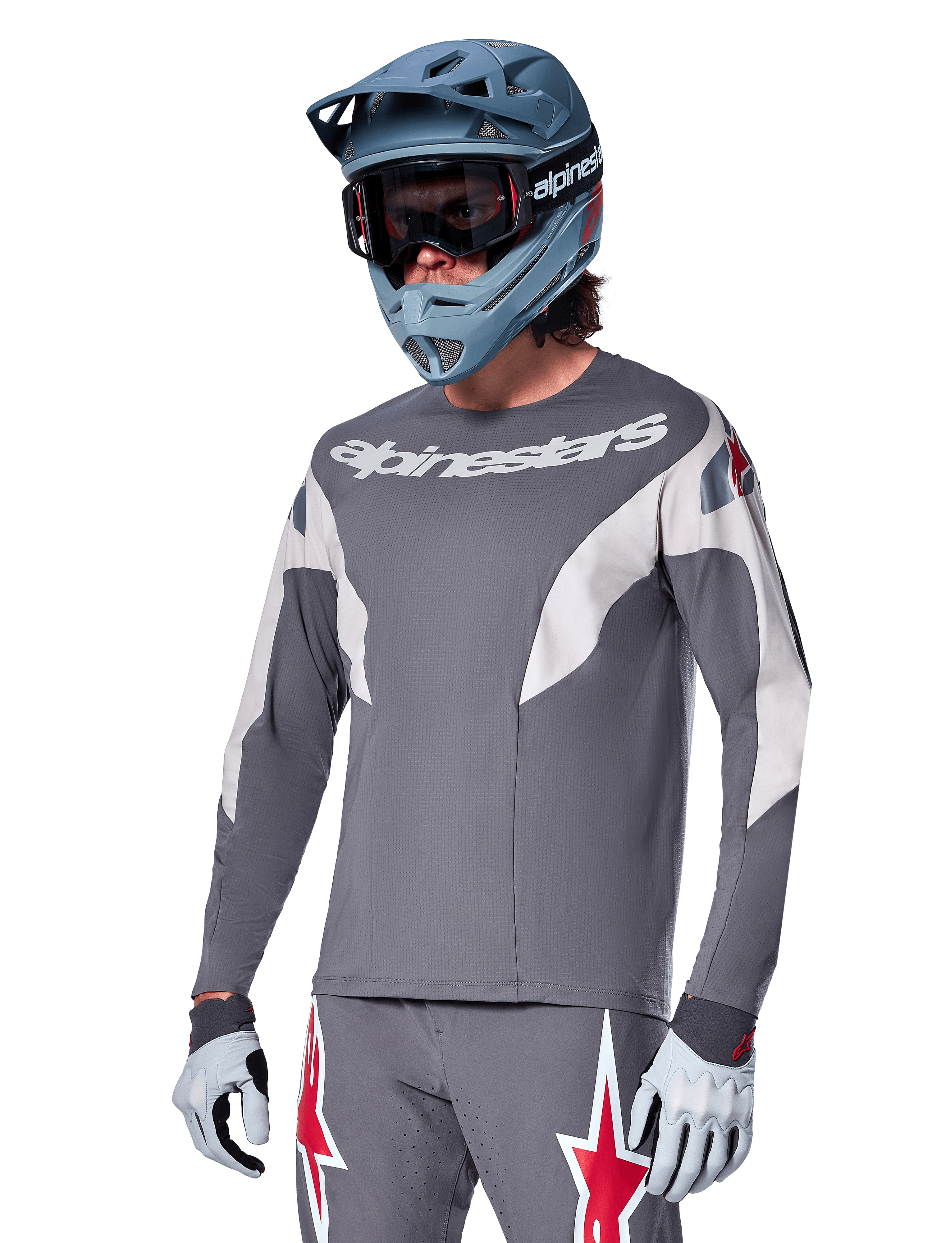 Alpinestars A-Supra Race Jersey de manga larga, gris oscuro con detalles blancos y rojos, gráficos de estilo de carreras, usado con pantalones grises a juego, casco integral azul y guantes blancos, equipo profesional de MTB y descenso