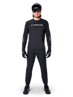 Jersey de manga larga Alpinestars A-Dura Switch, negro, usado por un ciclista de montaña con pantalones y casco negros a juego, con el logotipo de la marca en blanco en el pecho, ropa técnica para ciclismo de montaña