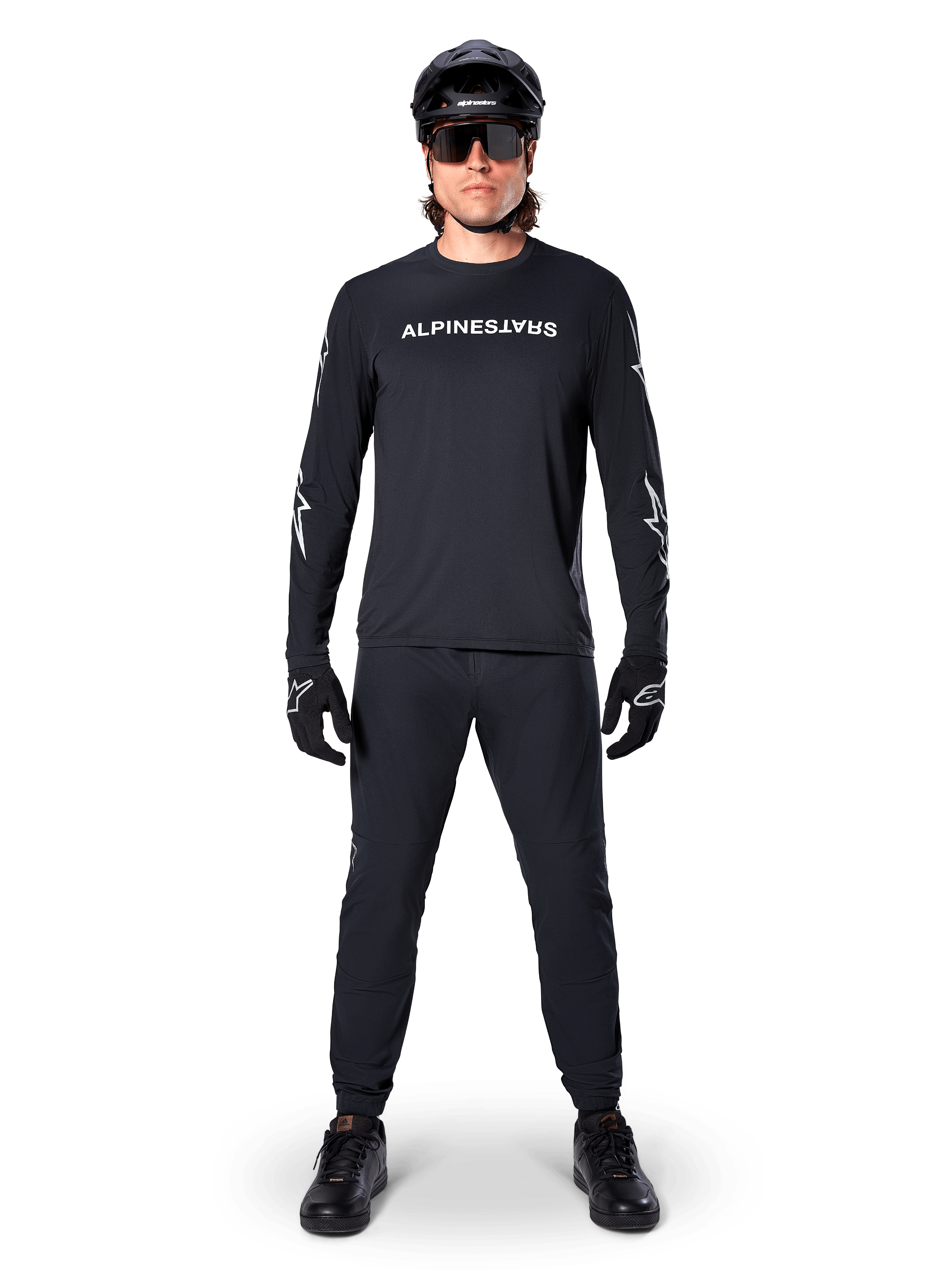Jersey de manga larga Alpinestars A-Dura Switch, negro, usado por un ciclista de montaña con pantalones y casco negros a juego, con el logotipo de la marca en blanco en el pecho, ropa técnica para ciclismo de montaña