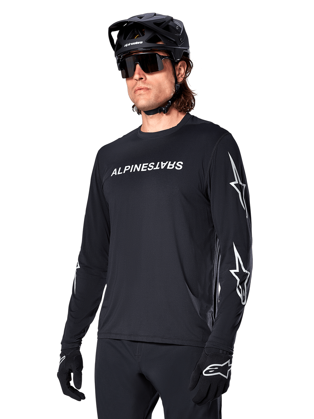 Ciclista masculino con jersey de manga larga Alpinestars A-Dura Switch, negro con marca en blanco y logotipos de estrella en las mangas, combinado con casco de MTB negro y gafas de sol, equipamiento de ciclismo de alto rendimiento para rutas todoterreno