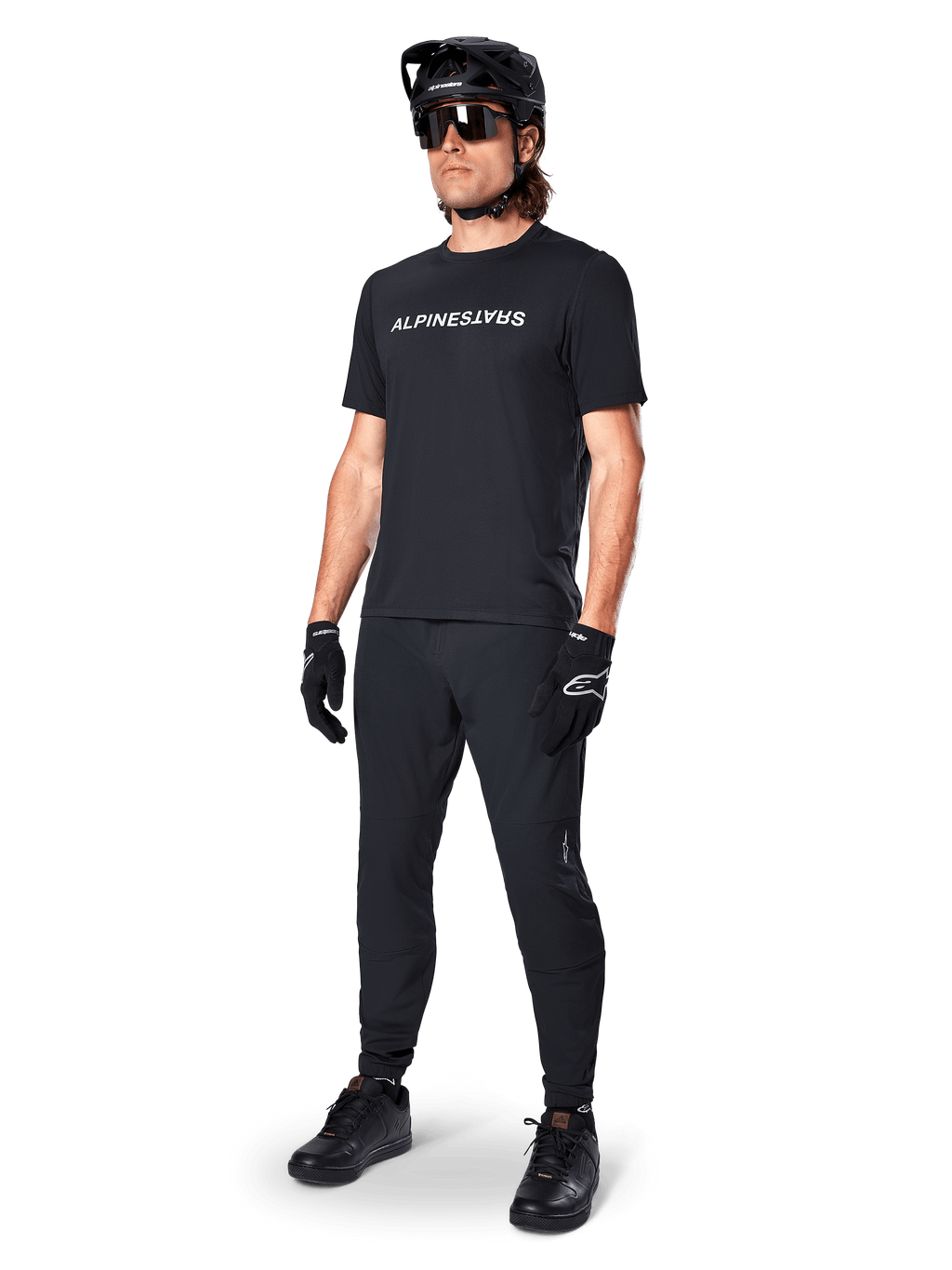 Camiseta de manga corta Alpinestars A-Dura Switch, negra, vestida por un modelo con pantalones de MTB, casco y guantes negros a juego, con el logotipo de Alpinestars en blanco sobre el pecho, ropa de alto rendimiento para ciclismo de montaña