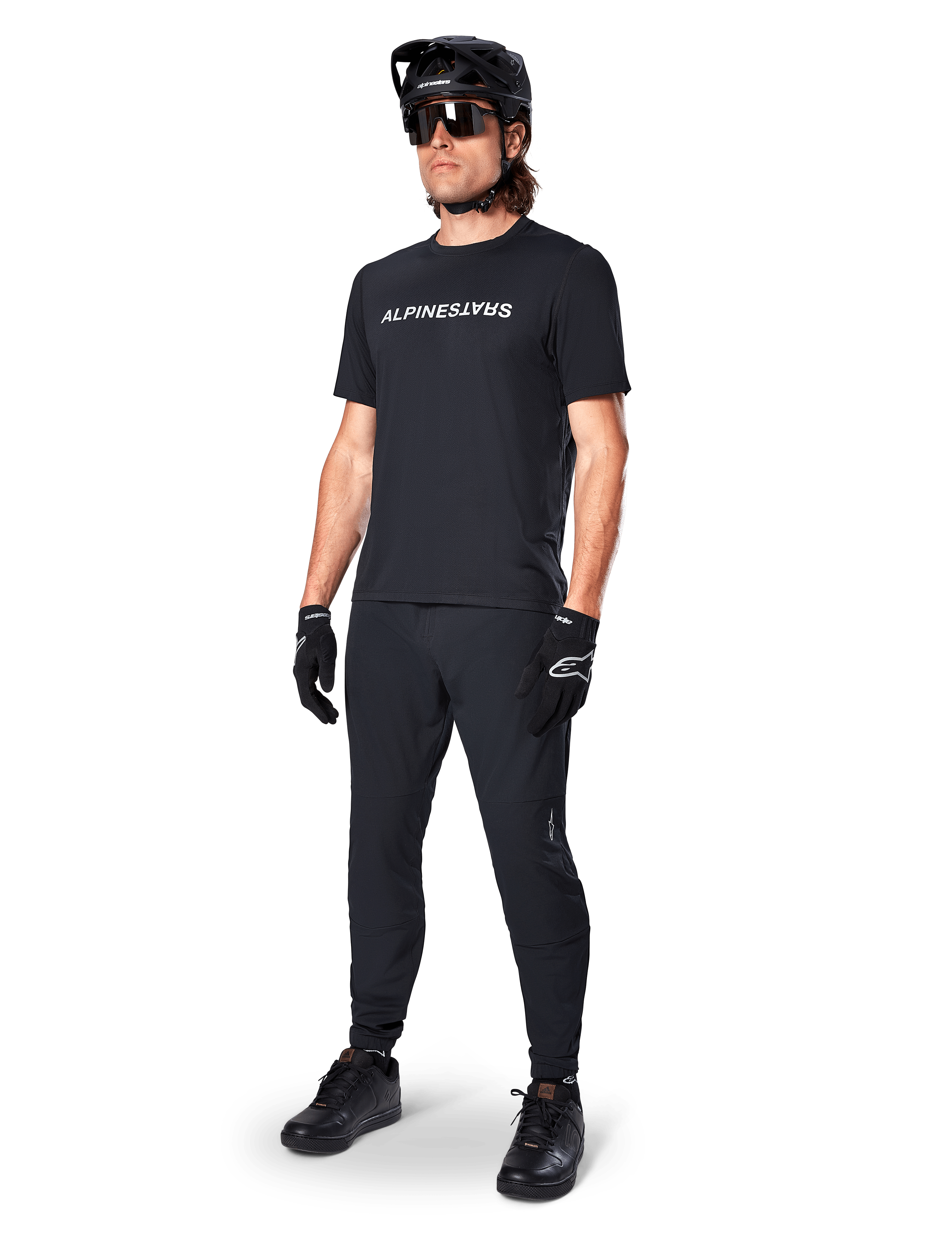 Camiseta de manga corta Alpinestars A-Dura Switch, negra, vestida por un modelo con pantalones de MTB, casco y guantes negros a juego, con el logotipo de Alpinestars en blanco sobre el pecho, ropa de alto rendimiento para ciclismo de montaña