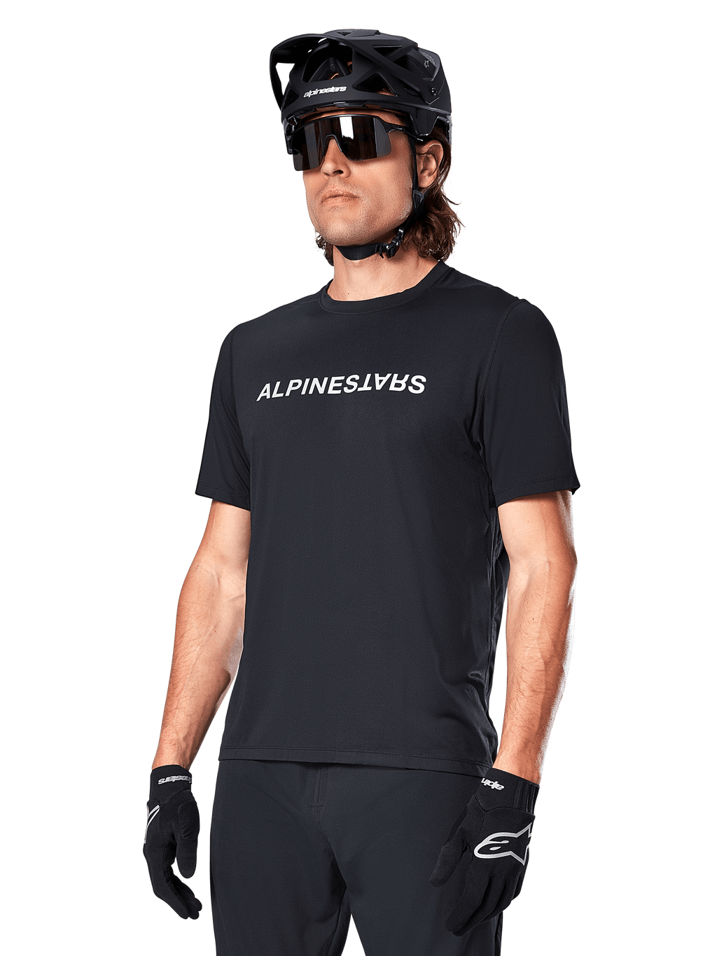 Jersey Alpinestars A-Dura Switch de manga corta, negro, con un logotipo blanco de la marca en el pecho, usado por un ciclista con casco de MTB negro y gafas de sol, ropa técnica diseñada para ciclismo de montaña