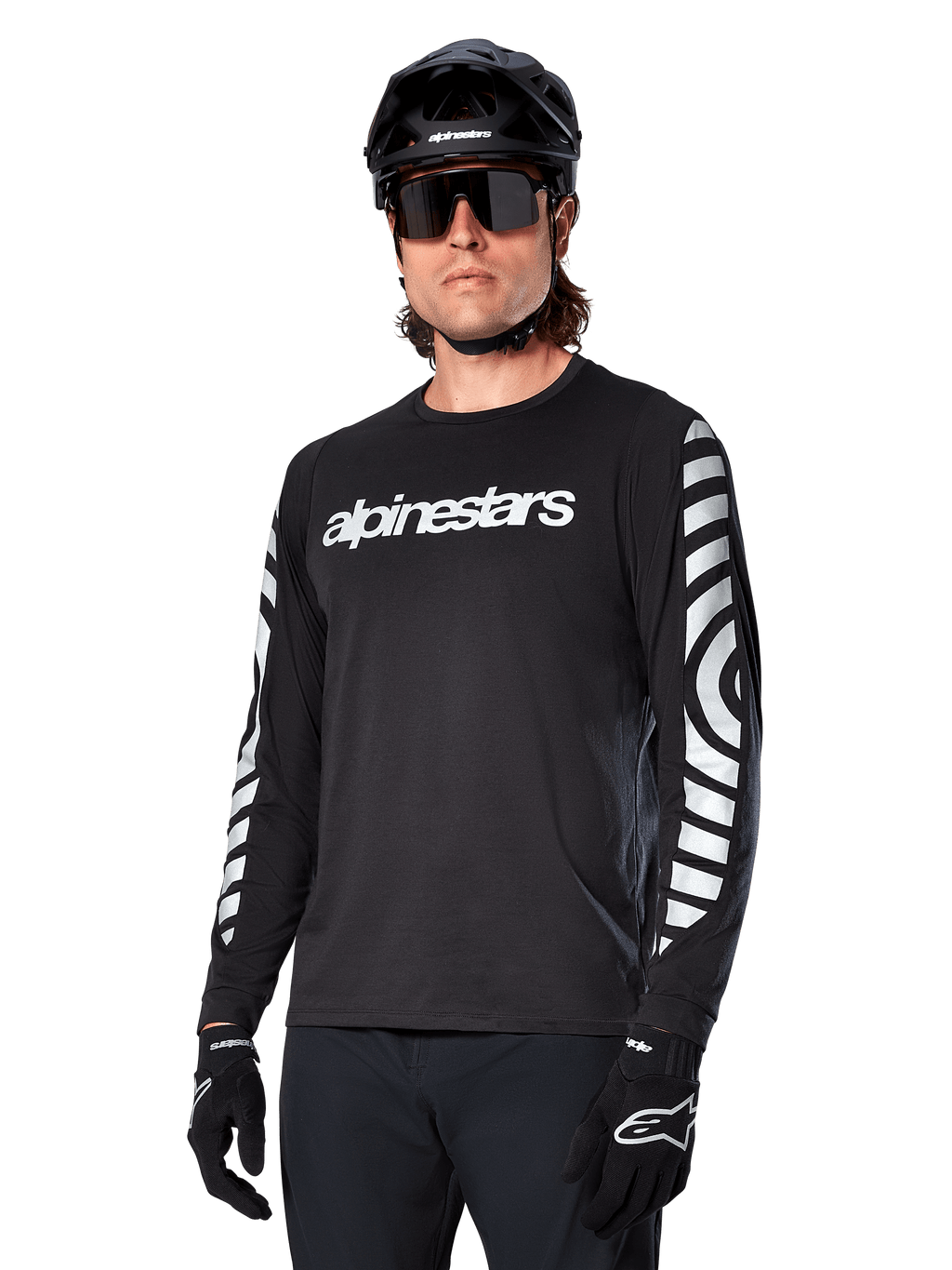 Alpinestars A-Dura Dri Oscar Jersey de manga larga, jersey de ciclismo MTB, negro reflectante, con logotipo blanco en el pecho y llamativos gráficos circulares reflectantes en las mangas, usado con casco negro y gafas de sol, prenda técnica transpirable para ciclismo de montaña