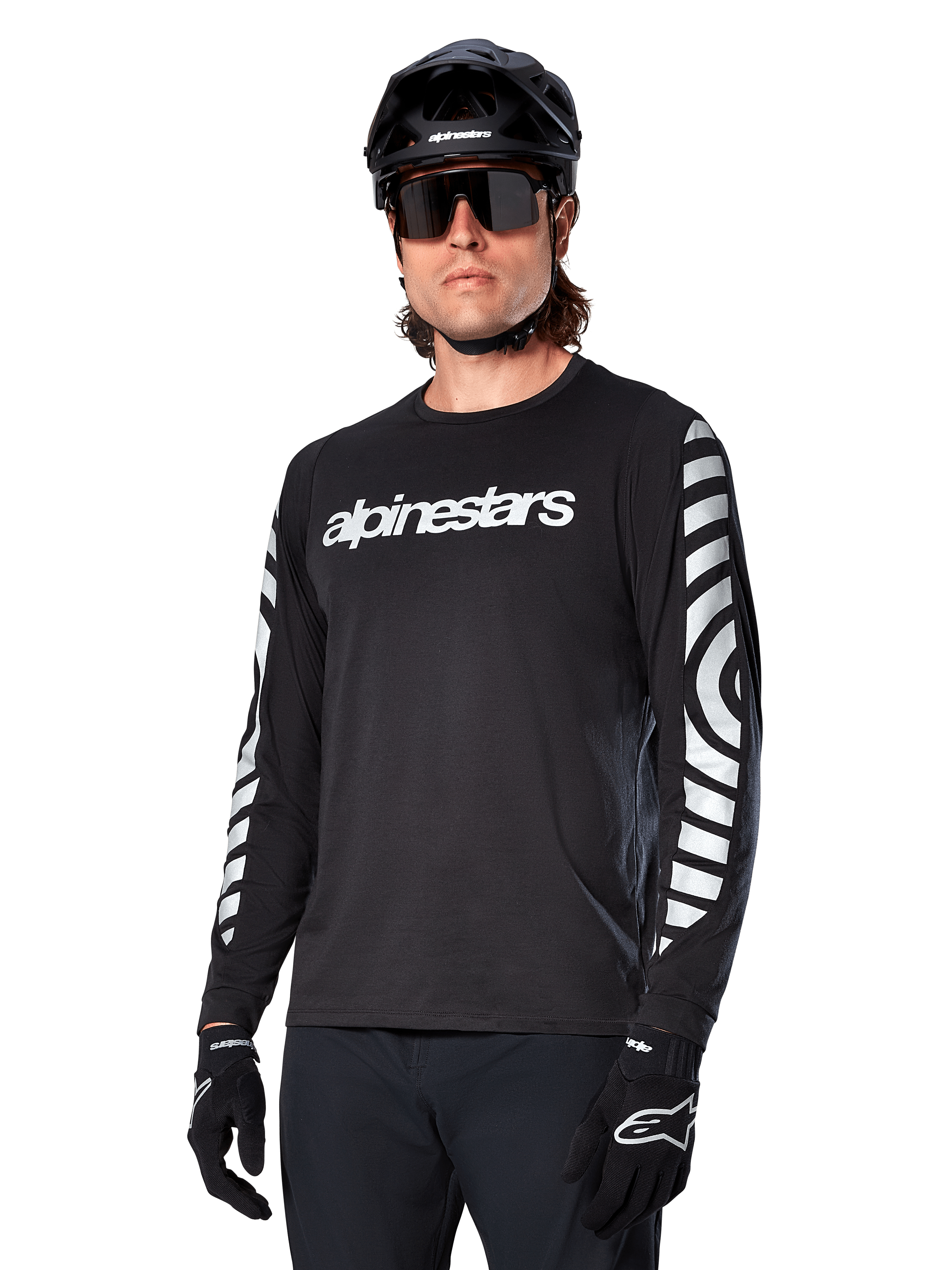Alpinestars A-Dura Dri Oscar Jersey de manga larga, jersey de ciclismo MTB, negro reflectante, con logotipo blanco en el pecho y llamativos gráficos circulares reflectantes en las mangas, usado con casco negro y gafas de sol, prenda técnica transpirable para ciclismo de montaña